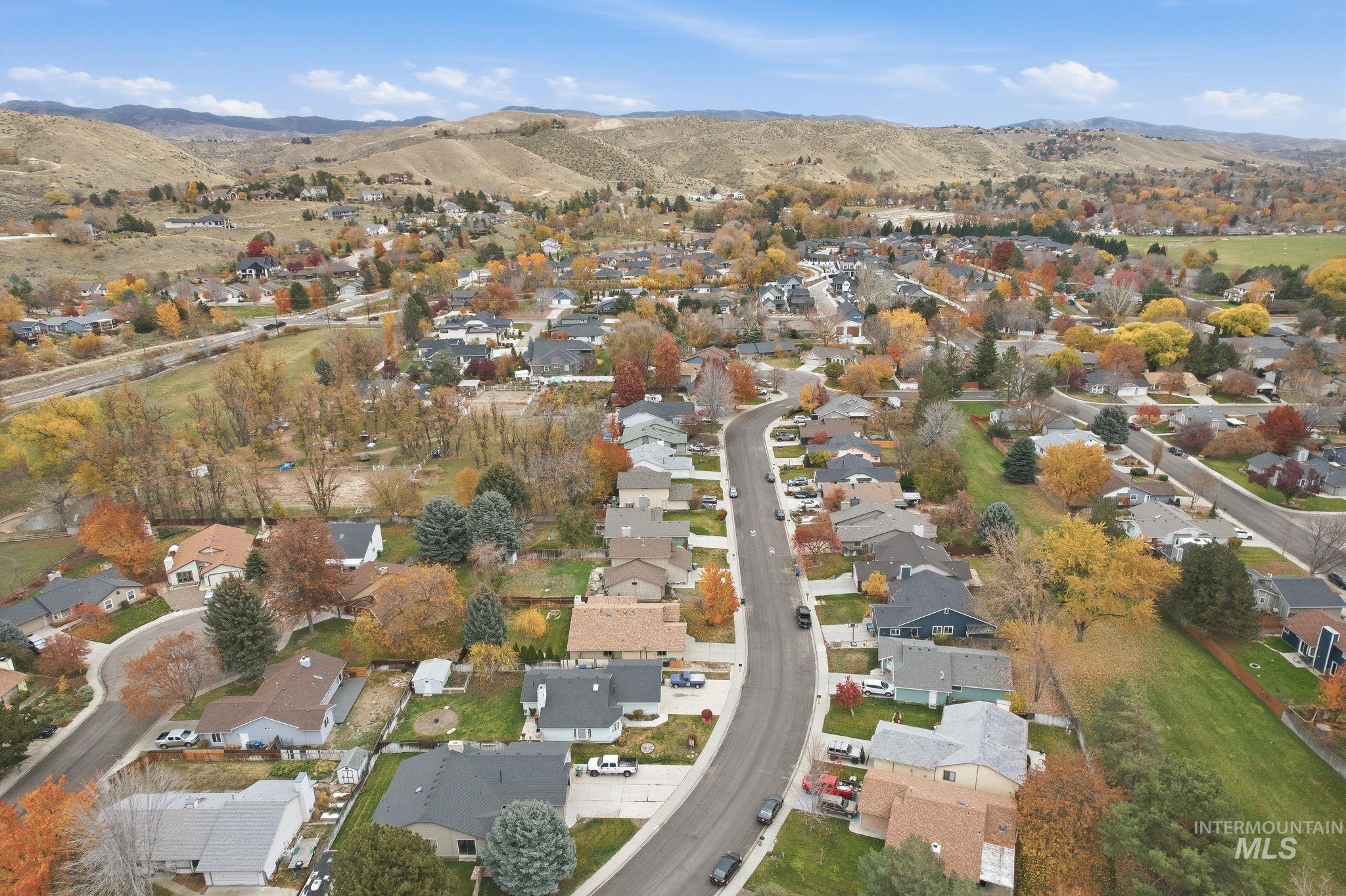 Aerial view of property and surrounding area with nearby suburban area and a mountain backdrop