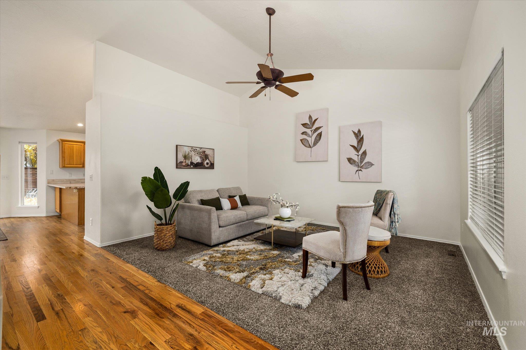 Living area with vaulted ceiling, a ceiling fan, and dark wood-style flooring