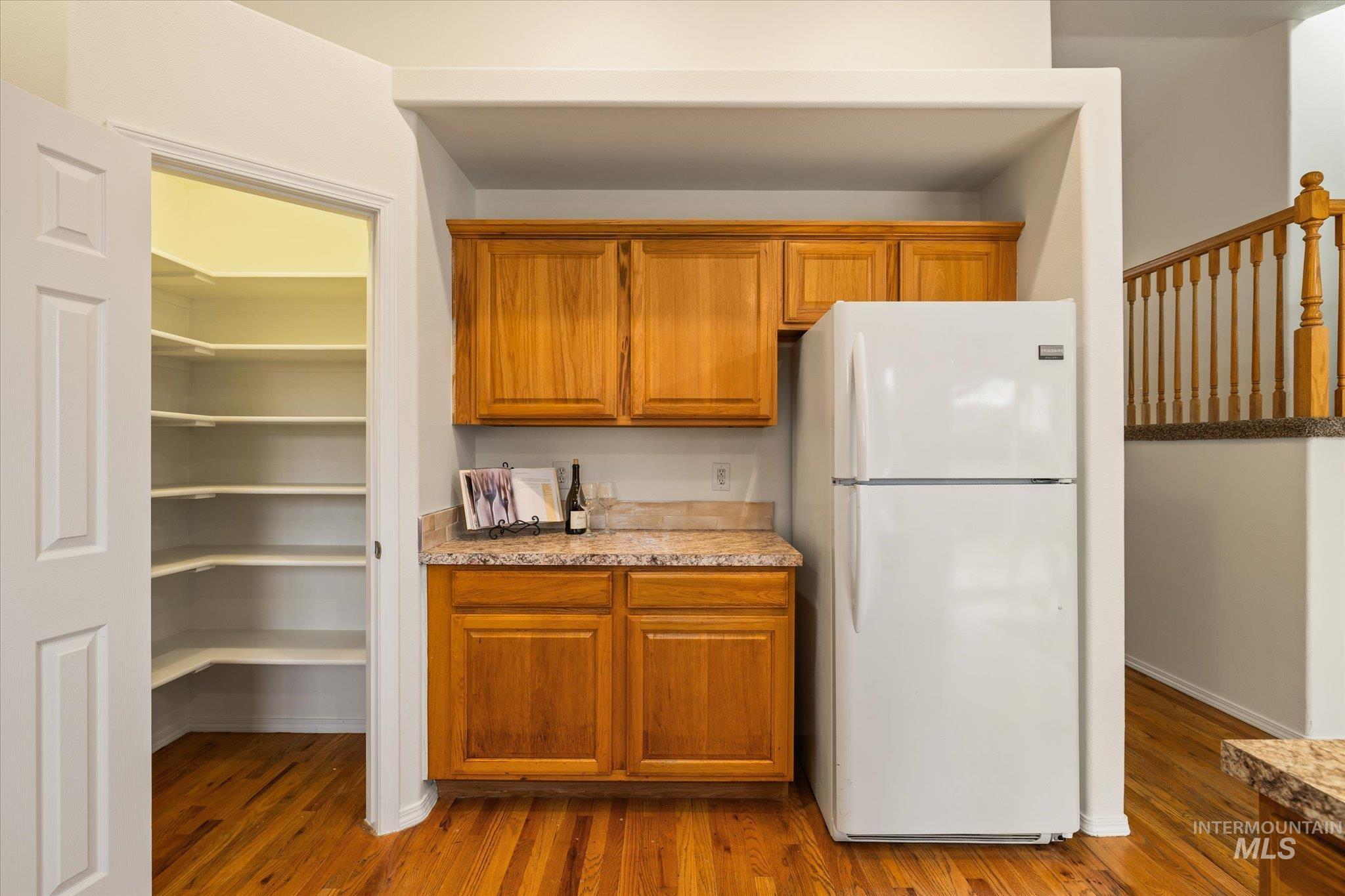 Kitchen with freestanding refrigerator, brown cabinetry, and light wood-type flooring