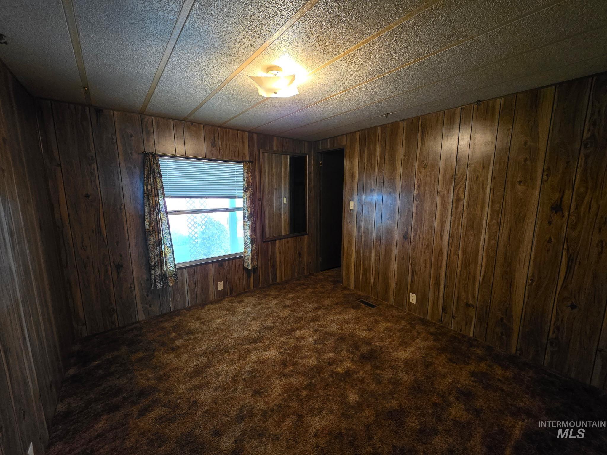 Empty room featuring carpet floors and wooden walls