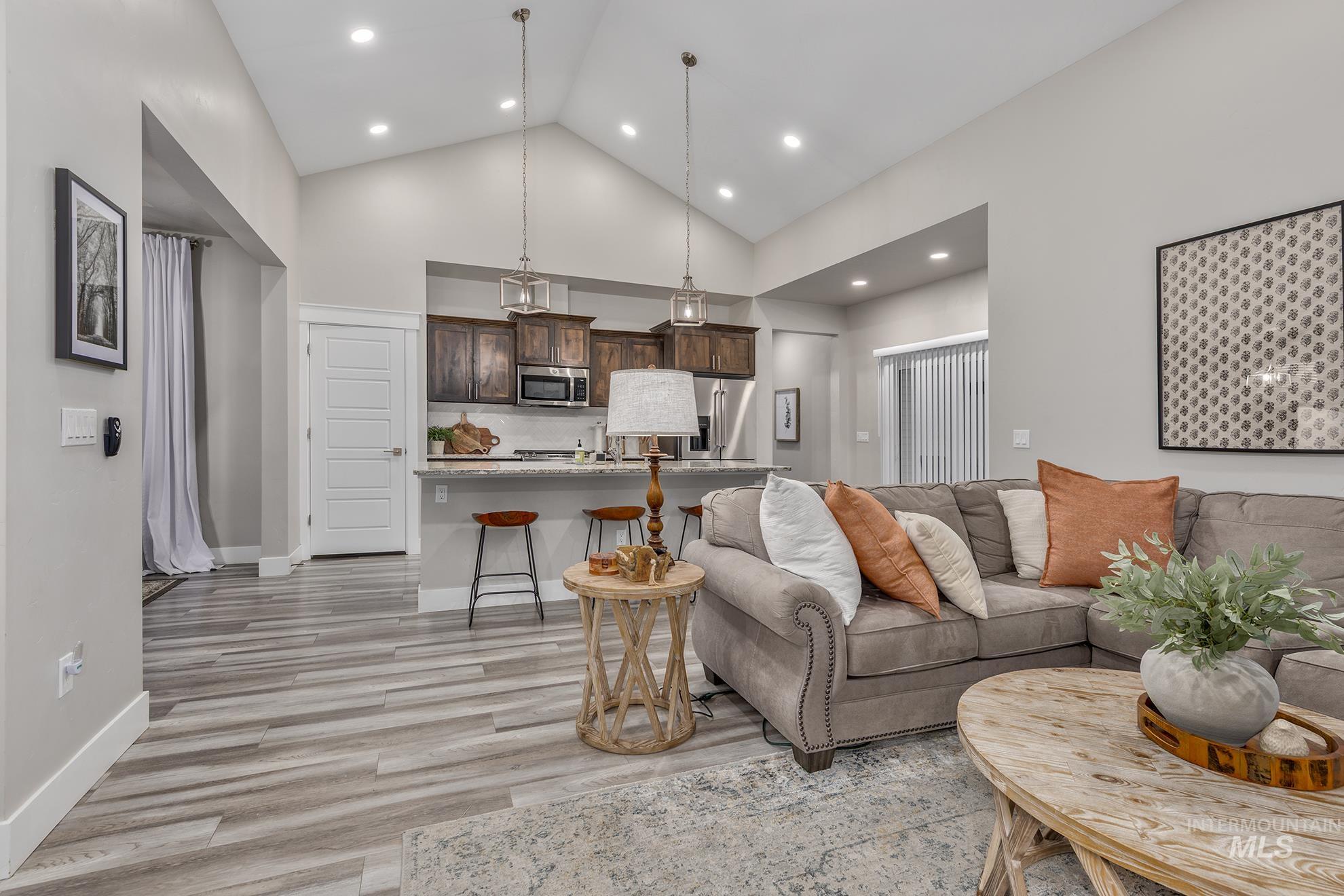 Living room with high vaulted ceiling, light wood-style floors, and recessed lighting