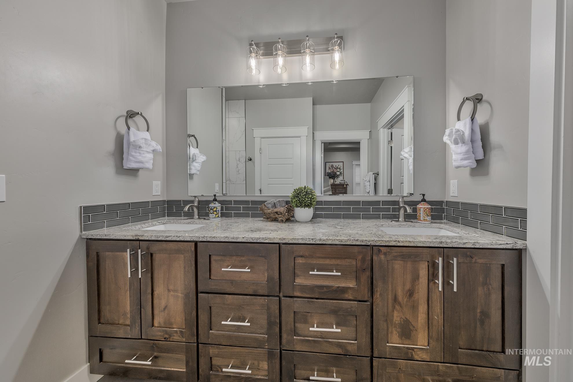 Bathroom featuring double vanity and backsplash
