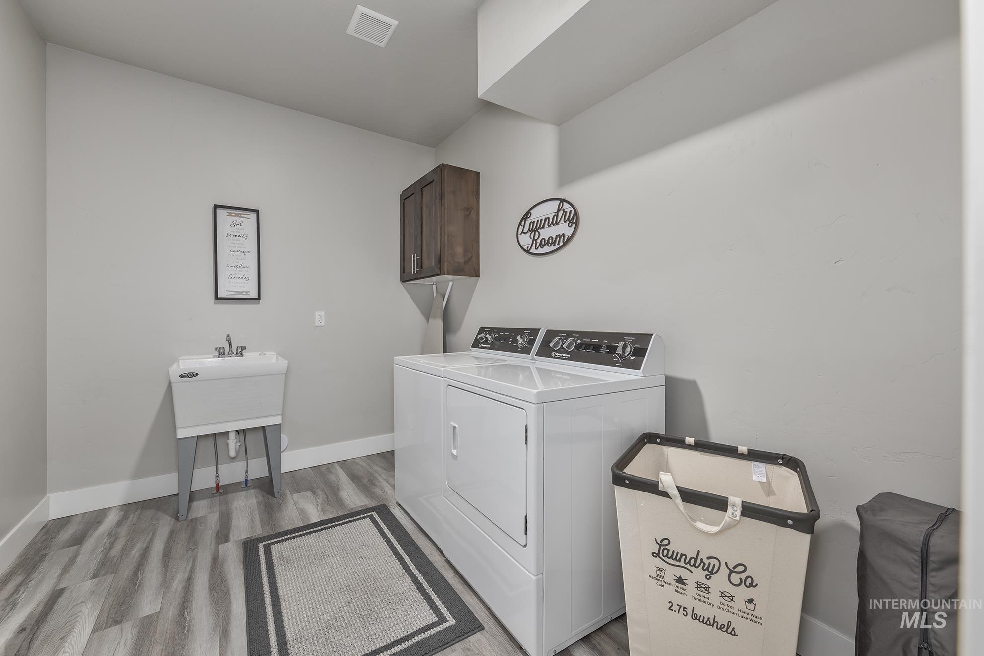 Washroom featuring light wood-style flooring, washing machine and dryer, and cabinet space