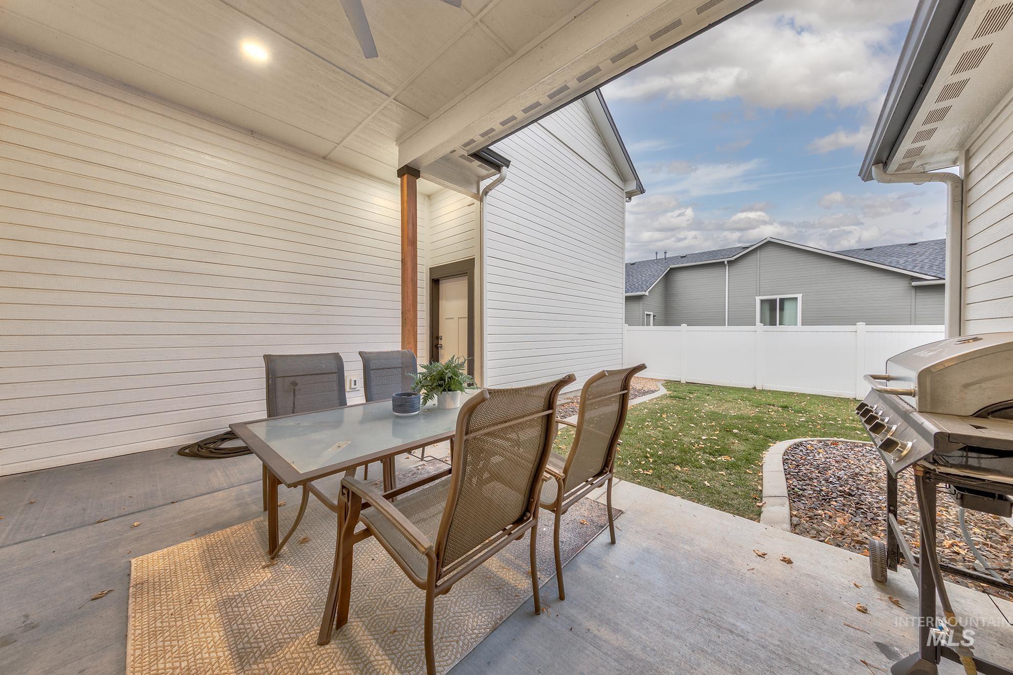 Fenced backyard with a patio area, outdoor dining area, area for grilling, and a ceiling fan
