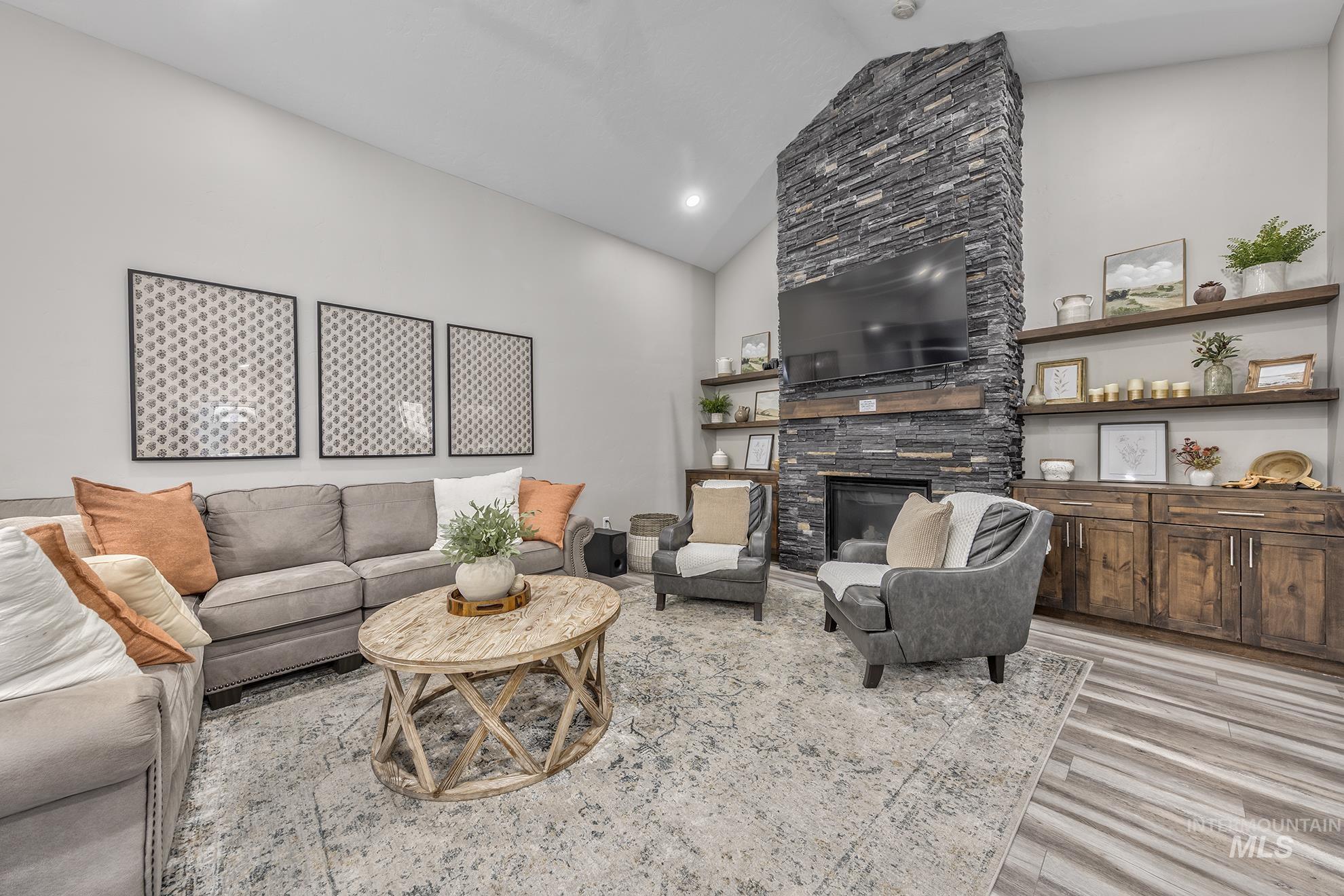 Living room featuring a fireplace, light wood-style flooring, and high vaulted ceiling