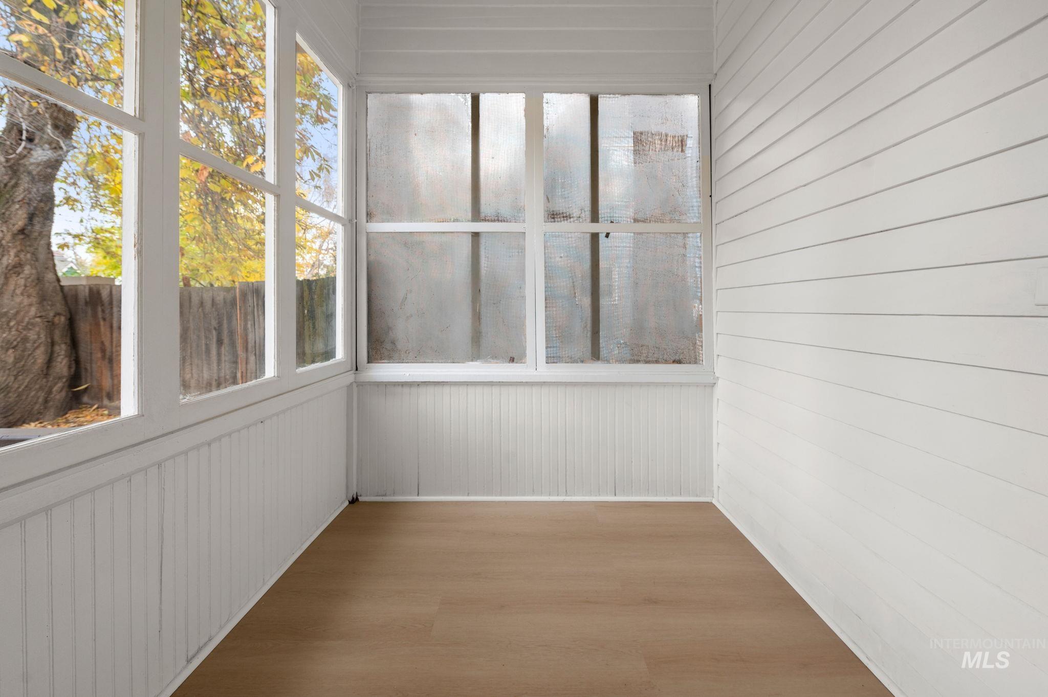 Unfurnished sunroom featuring wood walls and wood finished floors