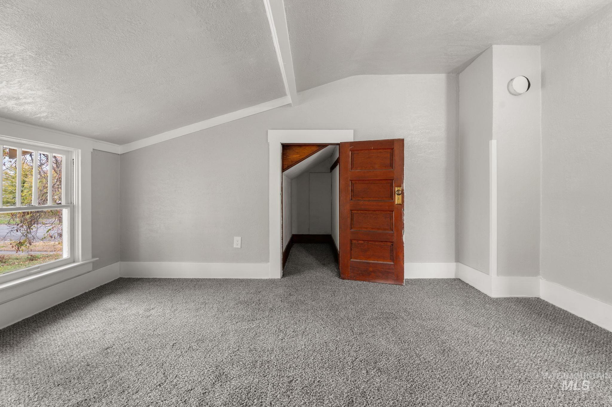 Additional living space featuring lofted ceiling, a textured ceiling, and carpet flooring