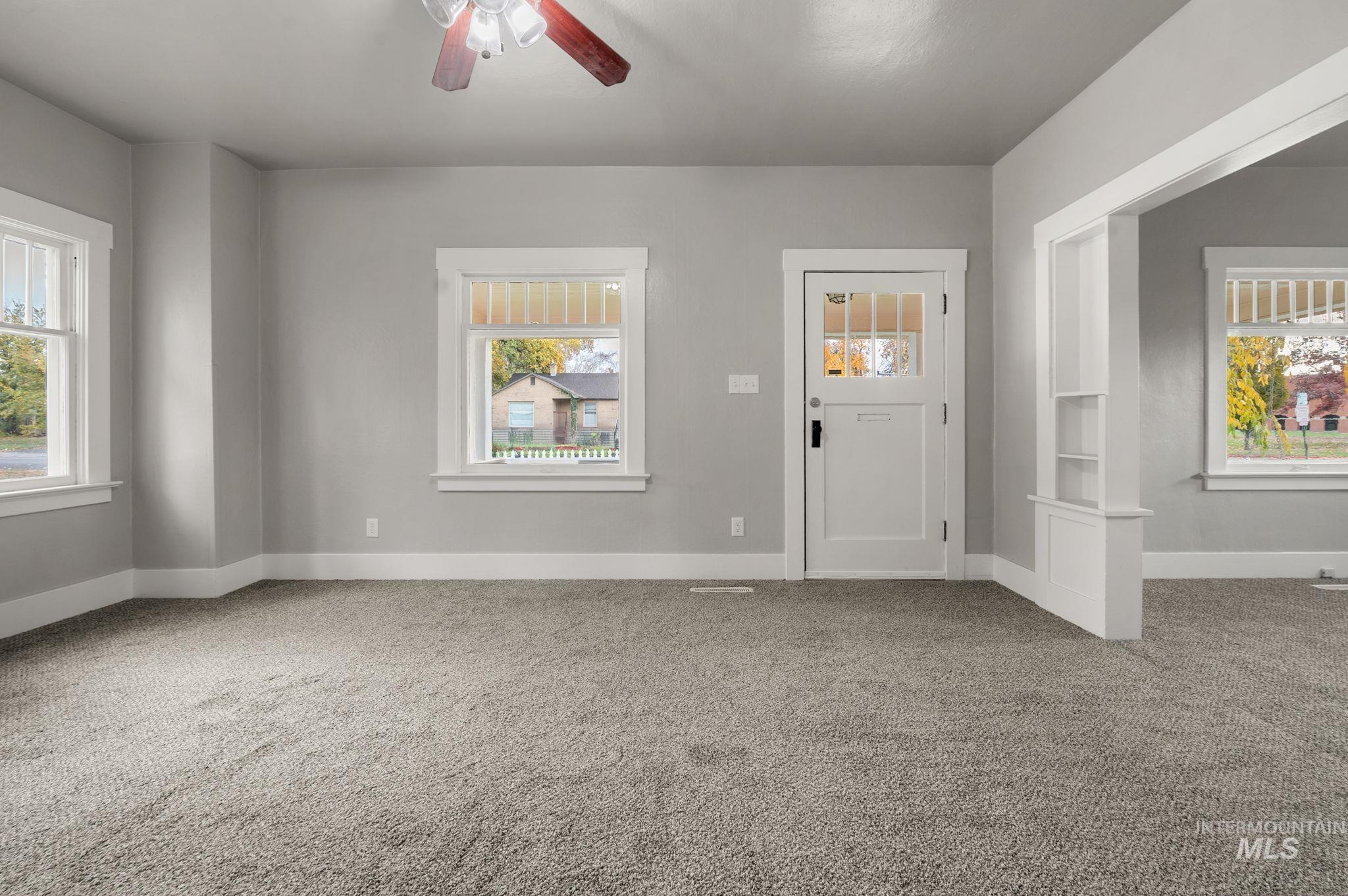 Entryway with healthy amount of natural light, light carpet, and ceiling fan