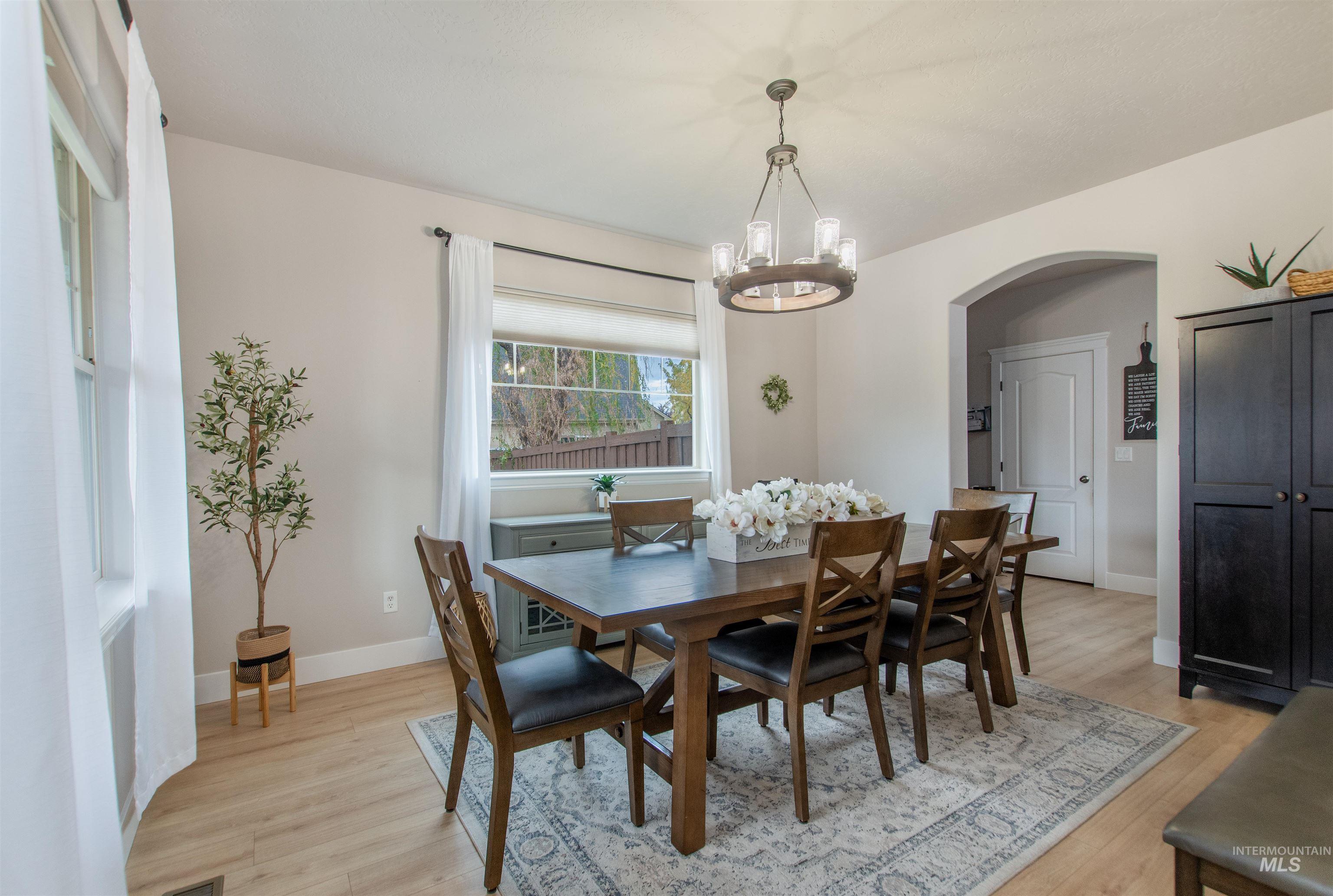 Dining area with light wood-style flooring, arched walkways, and a chandelier
