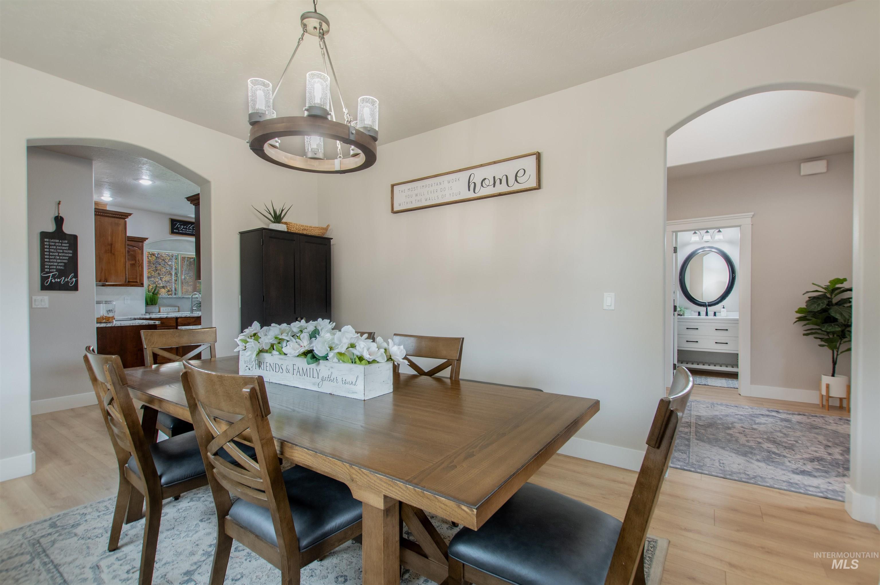 Dining space with arched walkways, light wood finished floors, and a chandelier