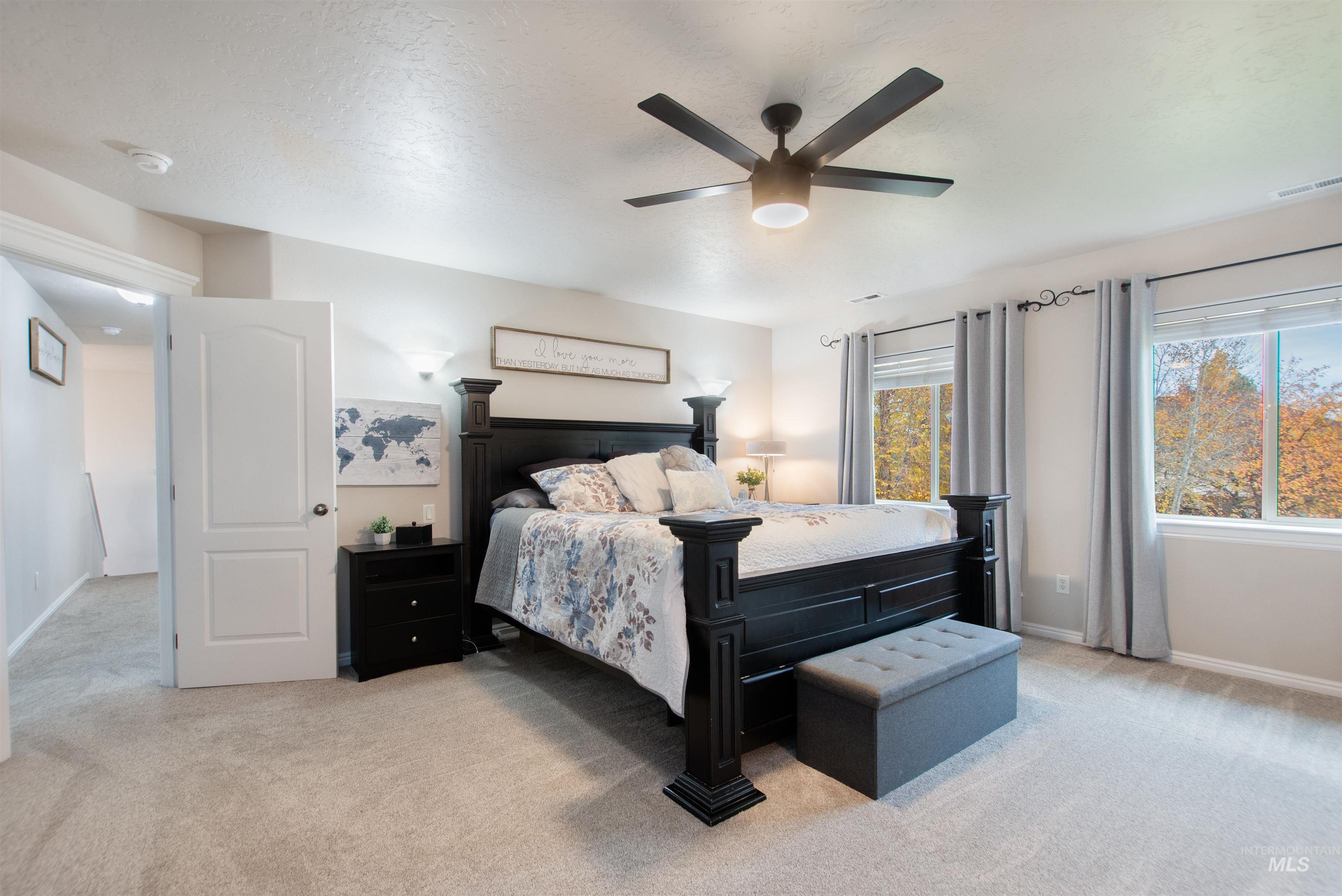 Bedroom with light carpet, a ceiling fan, and a textured ceiling