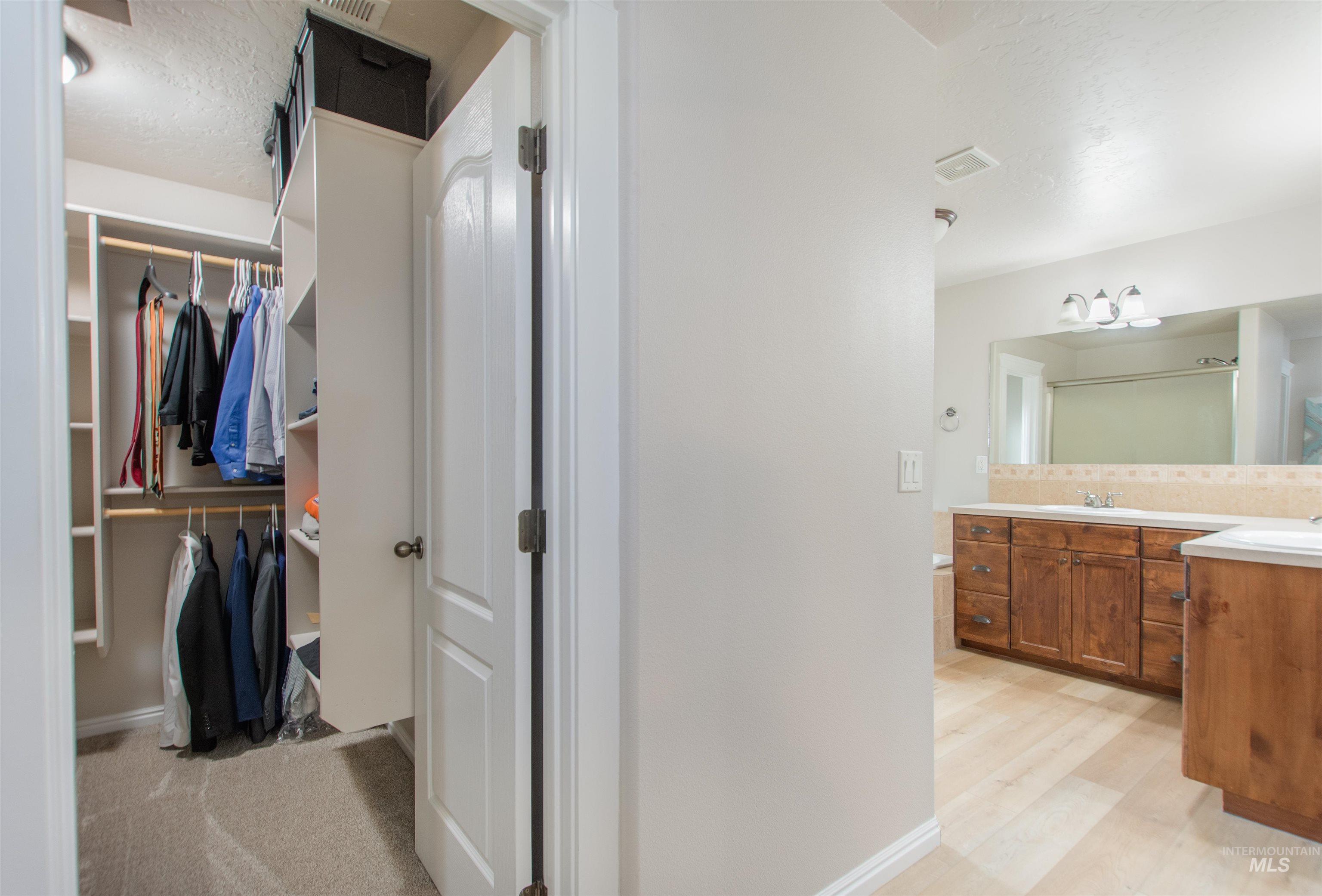 Bathroom featuring a textured ceiling, double vanity, and a spacious closet
