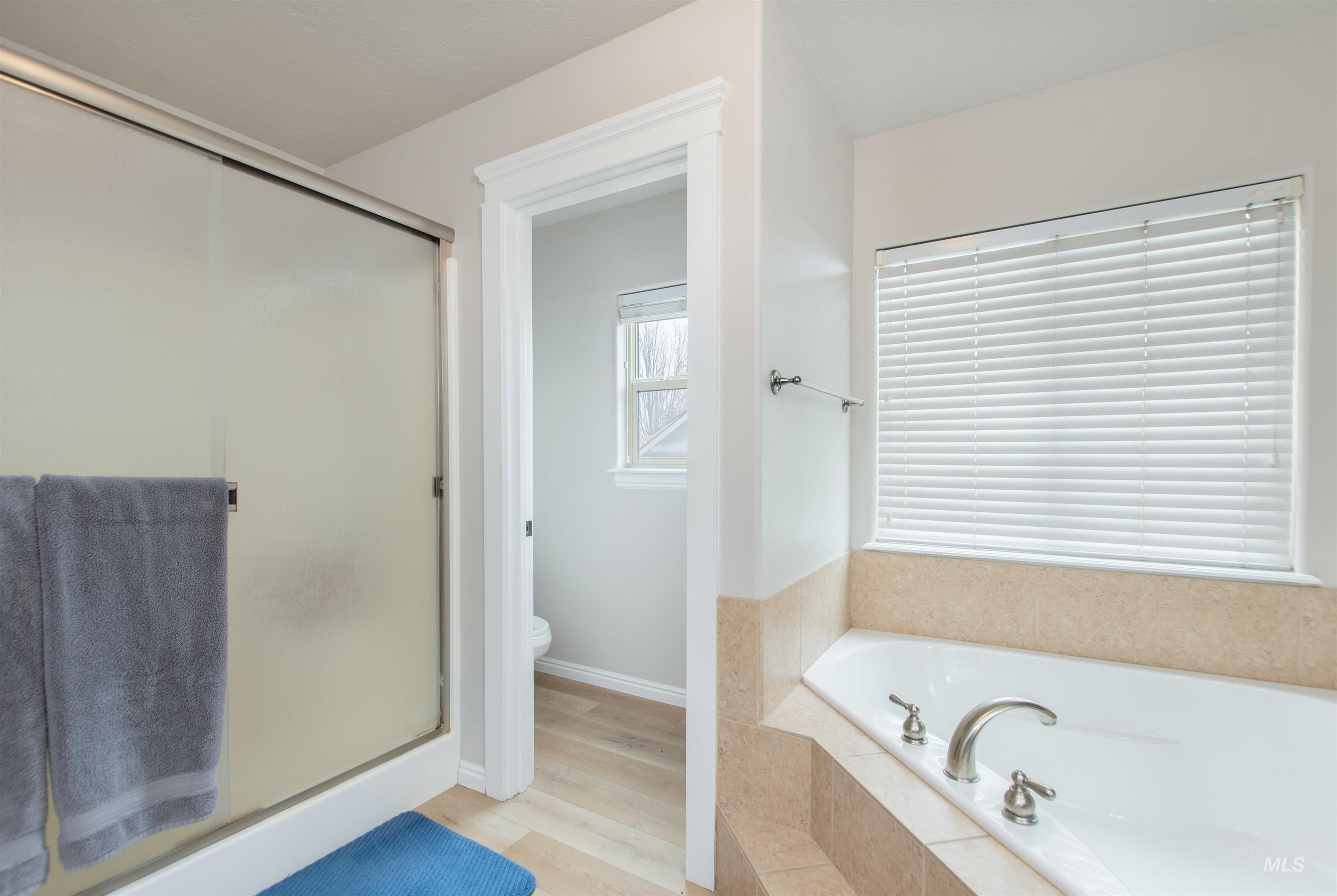 Bathroom with a stall shower, a bath, and wood finished floors
