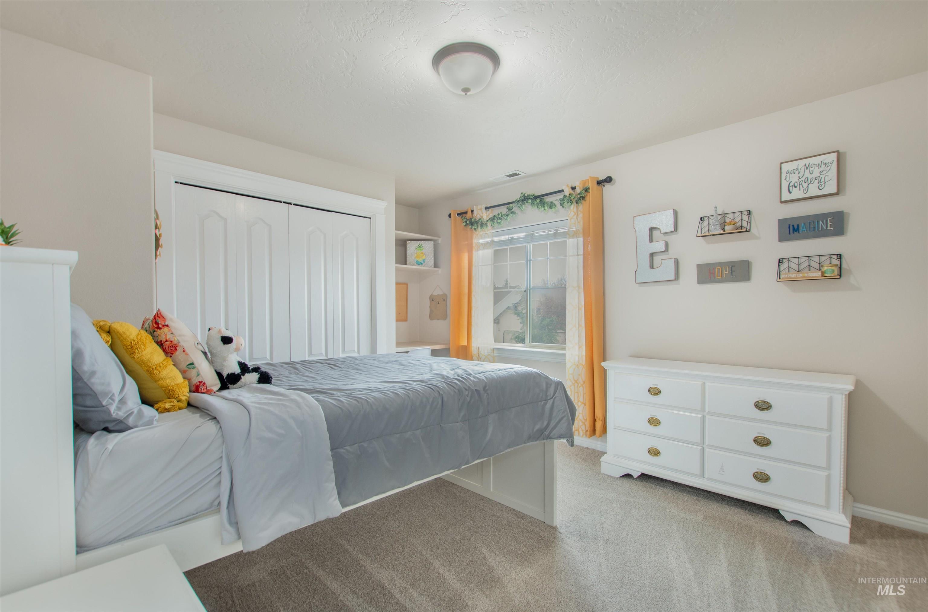 Bedroom with light colored carpet and a closet