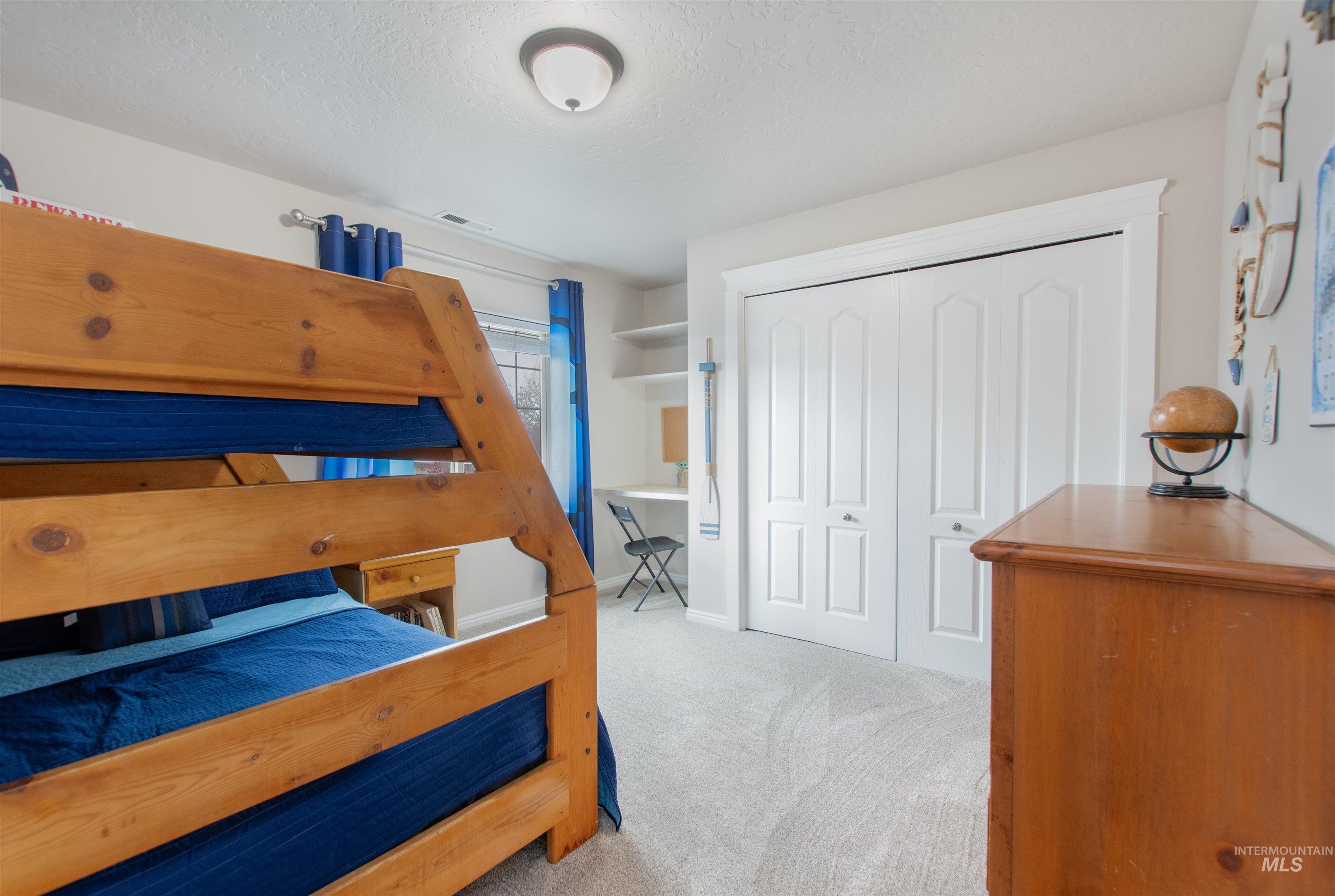 Bedroom featuring light colored carpet, a closet, and a textured ceiling