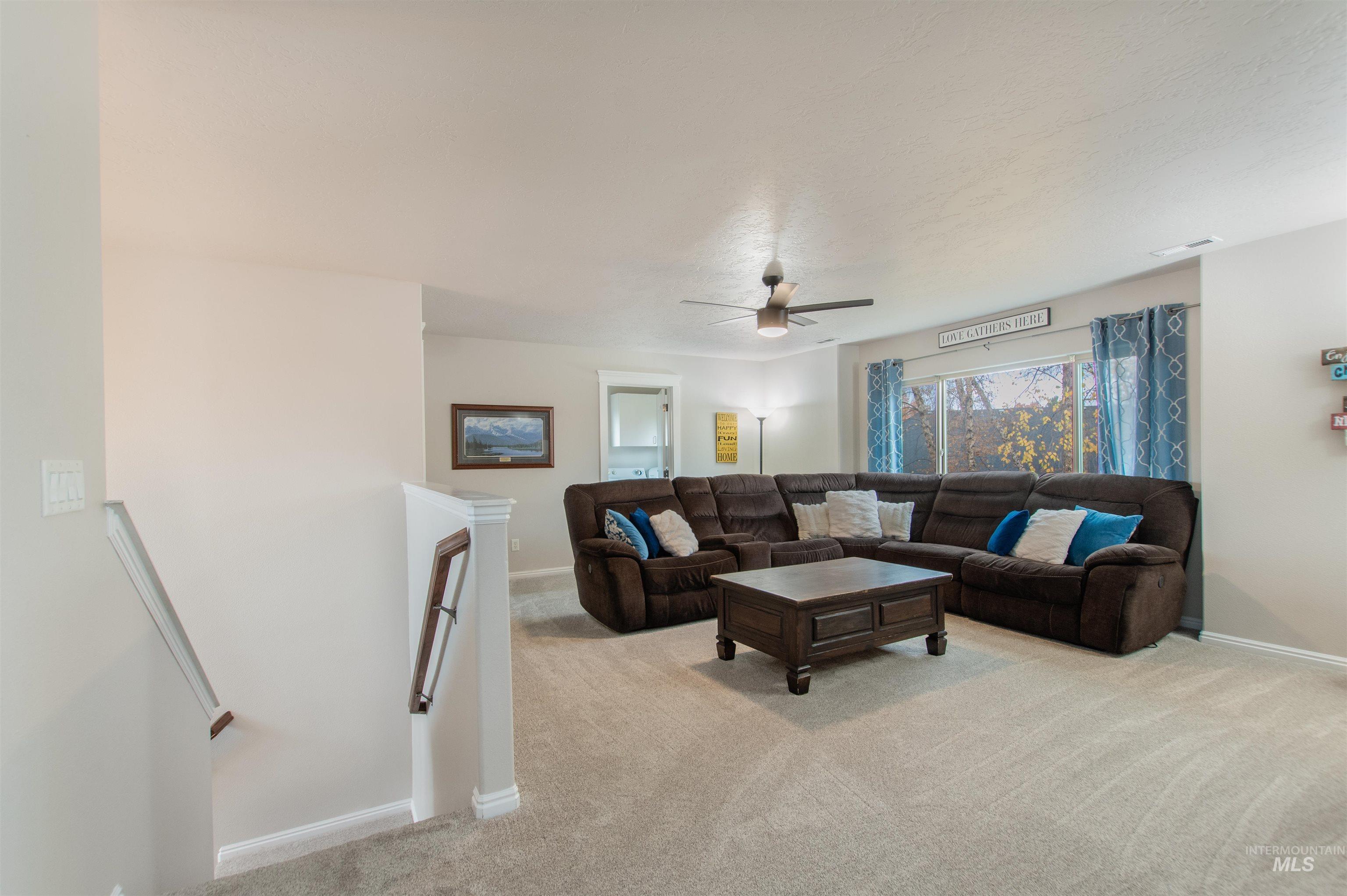 Living area featuring light carpet and ceiling fan