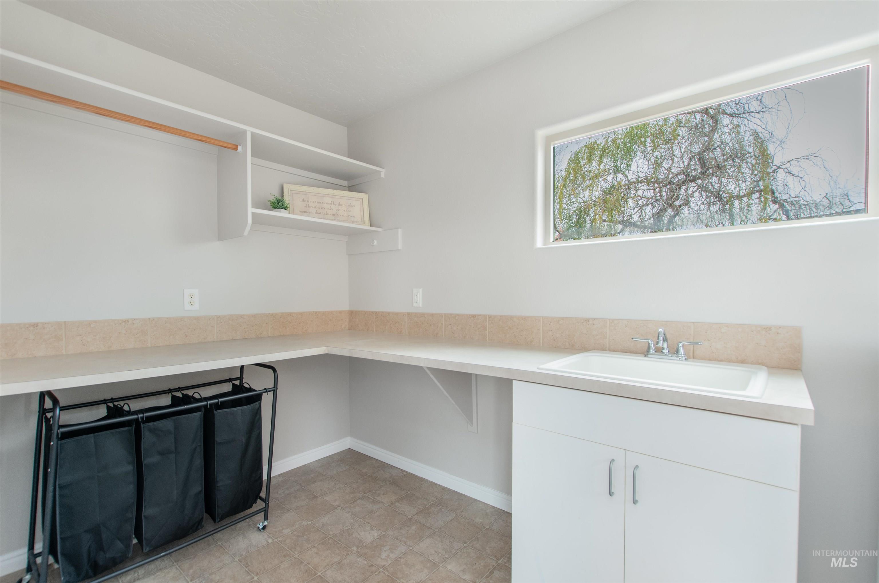 Kitchen with light countertops, white cabinets, and open shelves