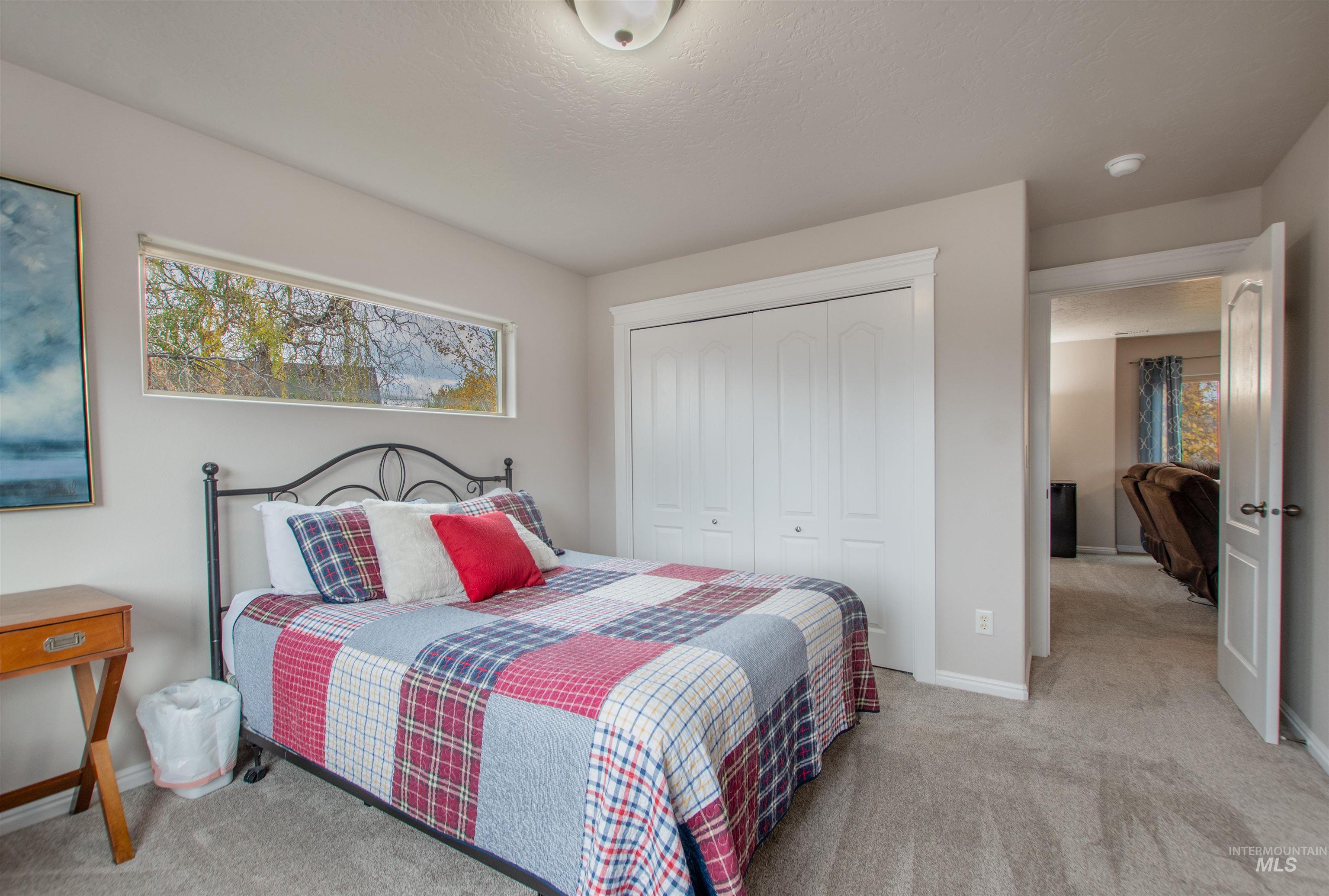 Bedroom with light carpet, a closet, and a textured ceiling