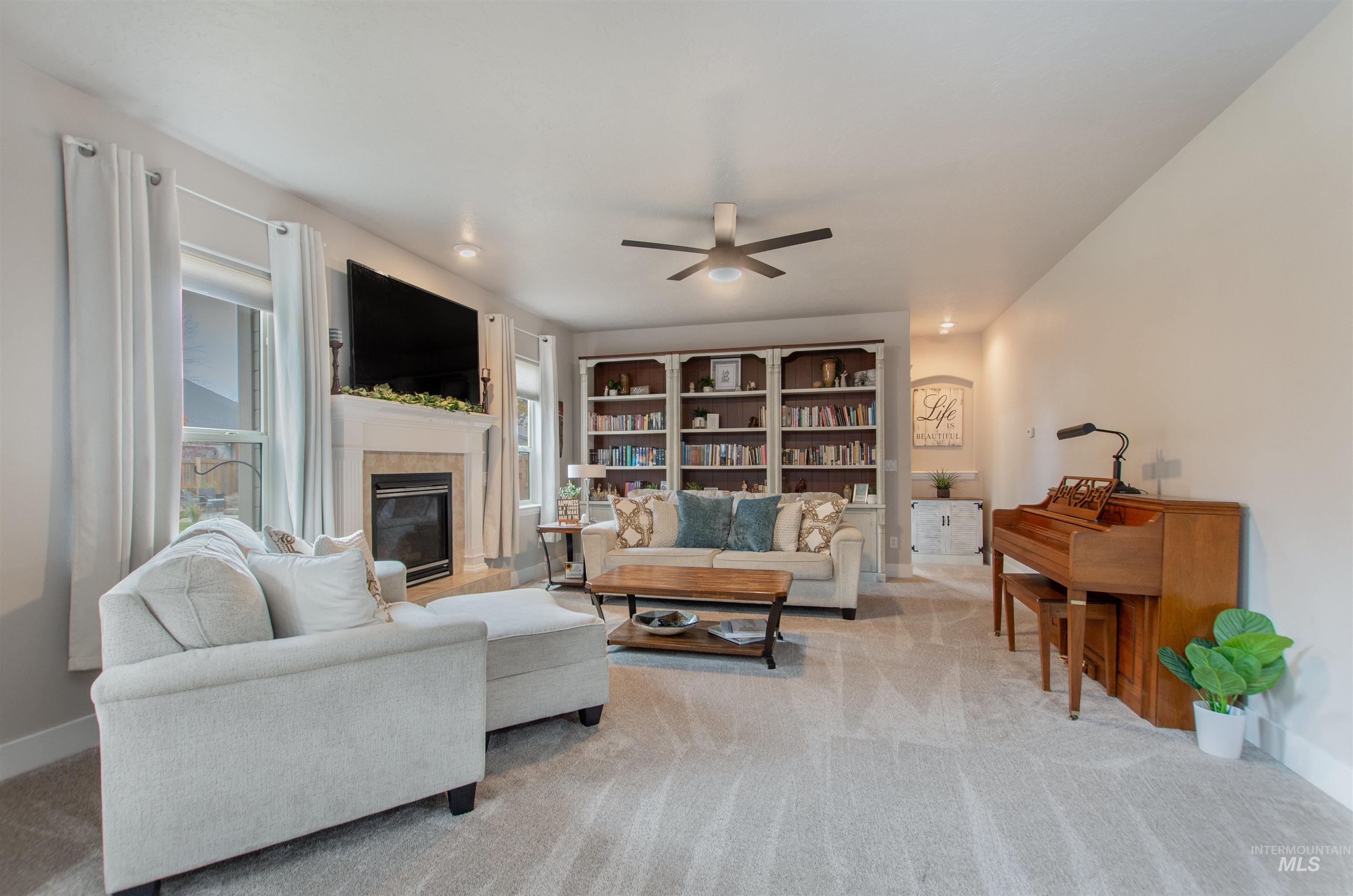 Living room with light colored carpet, a fireplace, and a ceiling fan