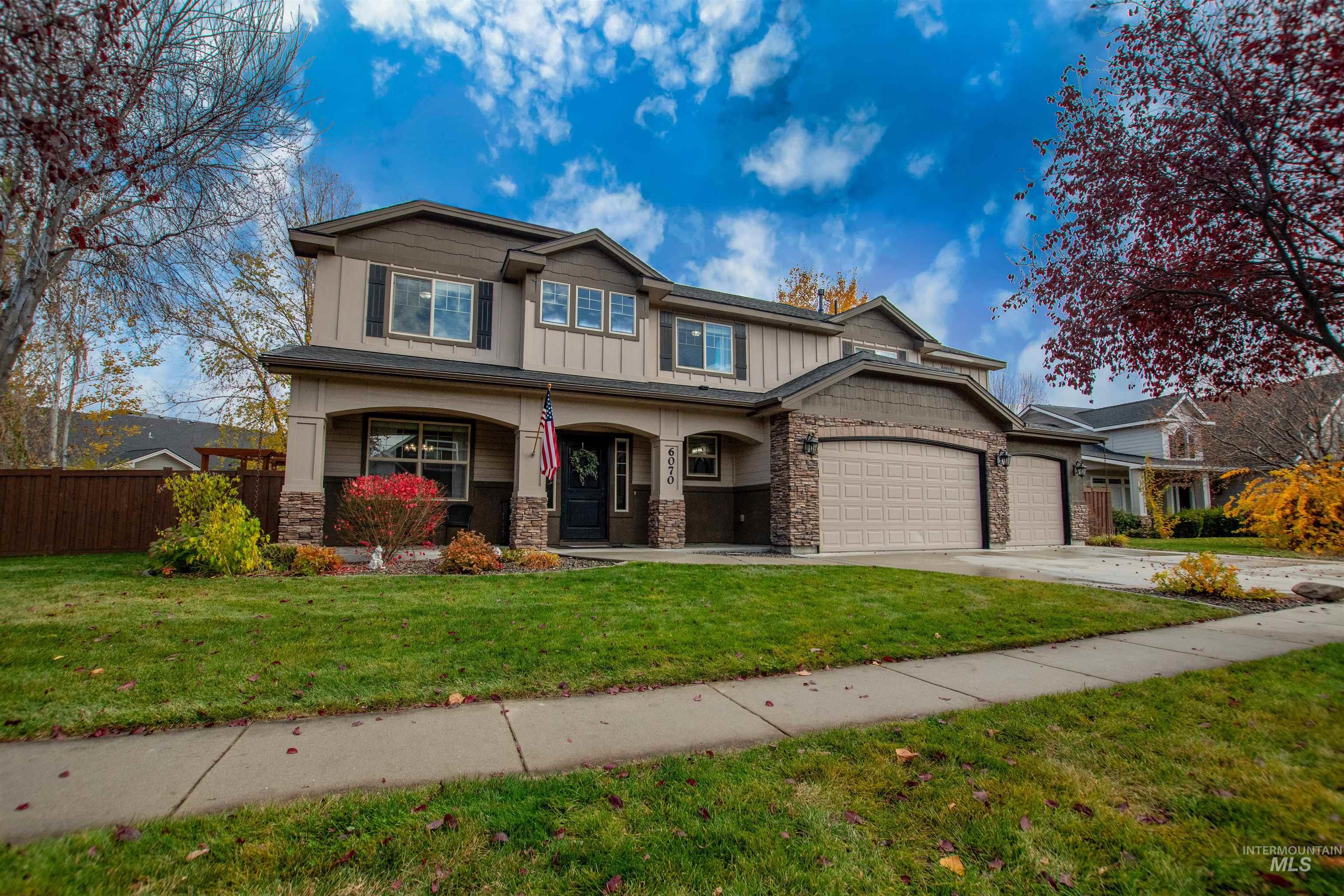 Craftsman-style house featuring a porch, board and batten siding, stone siding, and driveway