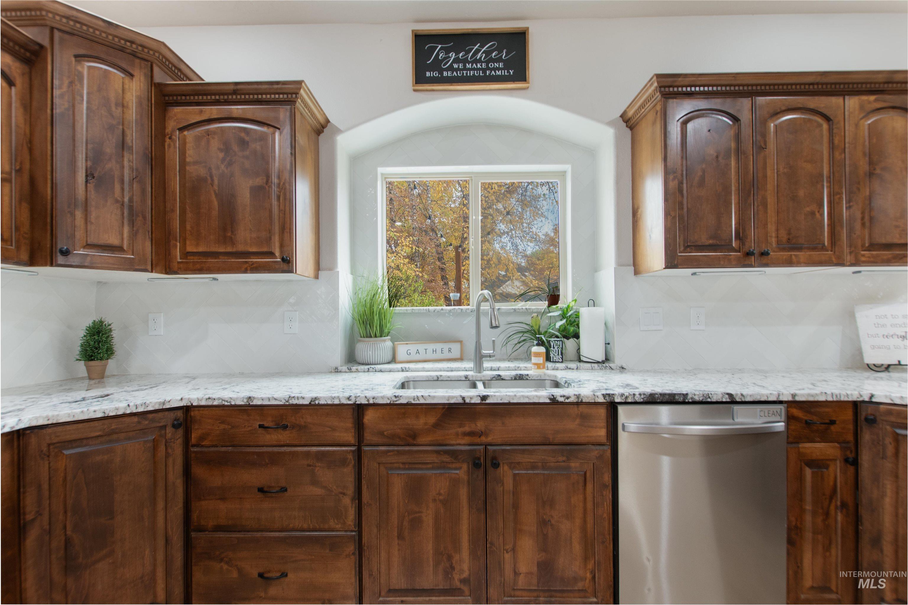Kitchen with dishwasher, light stone counters, and tasteful backsplash