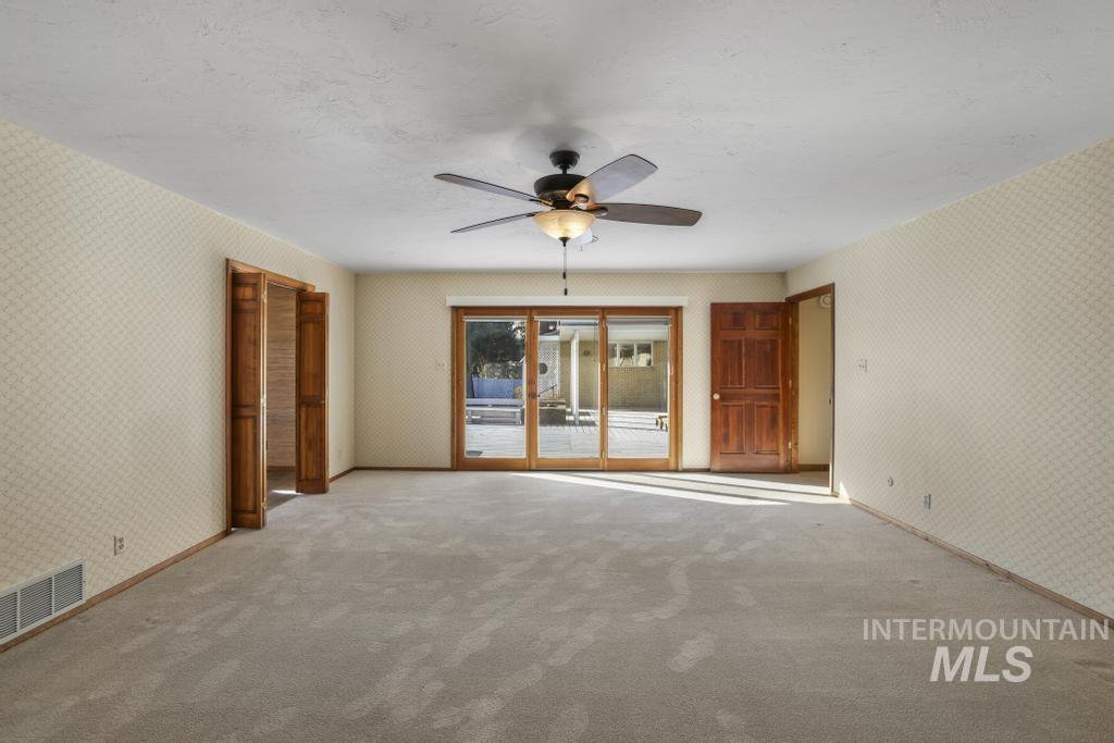 Carpeted spare room with wallpapered walls, ceiling fan, and a textured ceiling