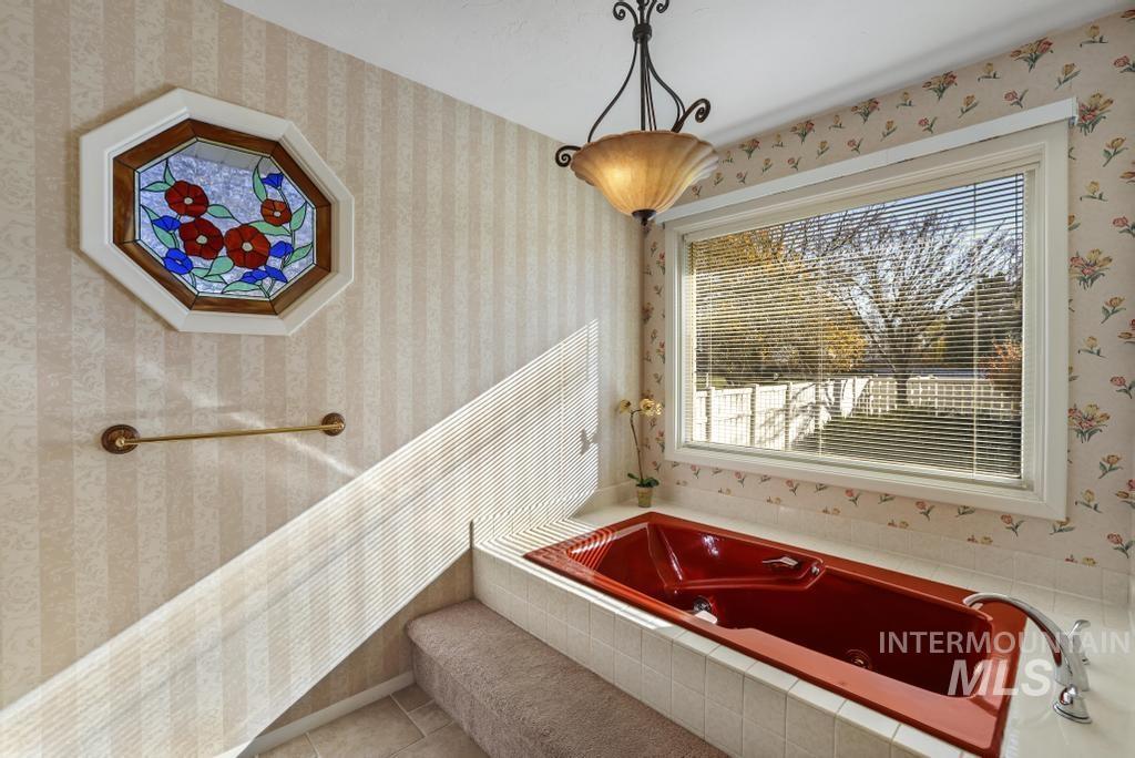 Bathroom with wallpapered walls, a tub with jets, and tile patterned flooring