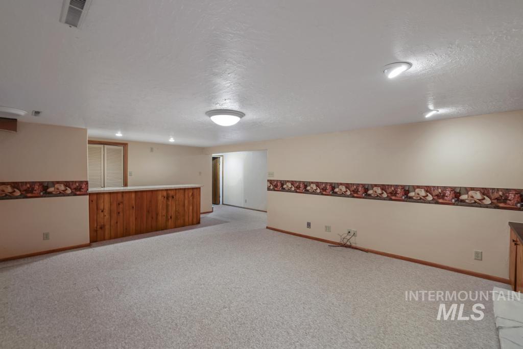 Empty room featuring a textured ceiling and light colored carpet