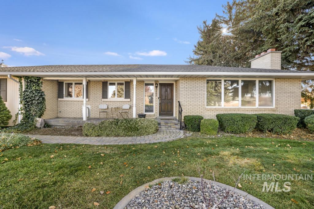 Single story home featuring a front lawn, a porch, brick siding, and a chimney