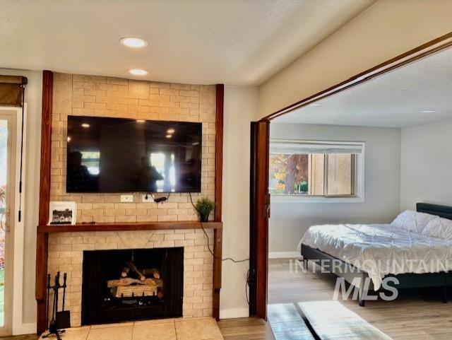 Bedroom featuring wood finished floors, a fireplace, and recessed lighting