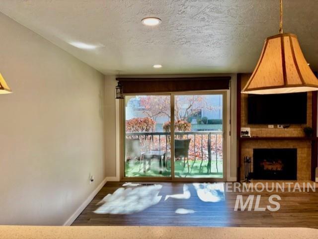 Unfurnished living room with a textured ceiling, a large fireplace, wood finished floors, and recessed lighting