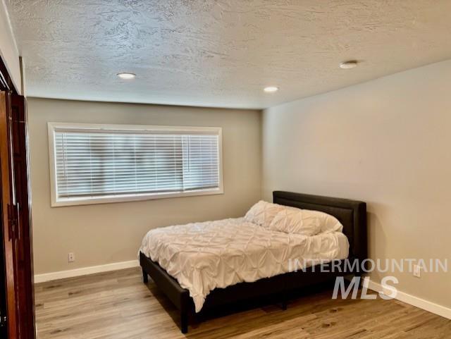 Bedroom with a textured ceiling, light wood-type flooring, and recessed lighting