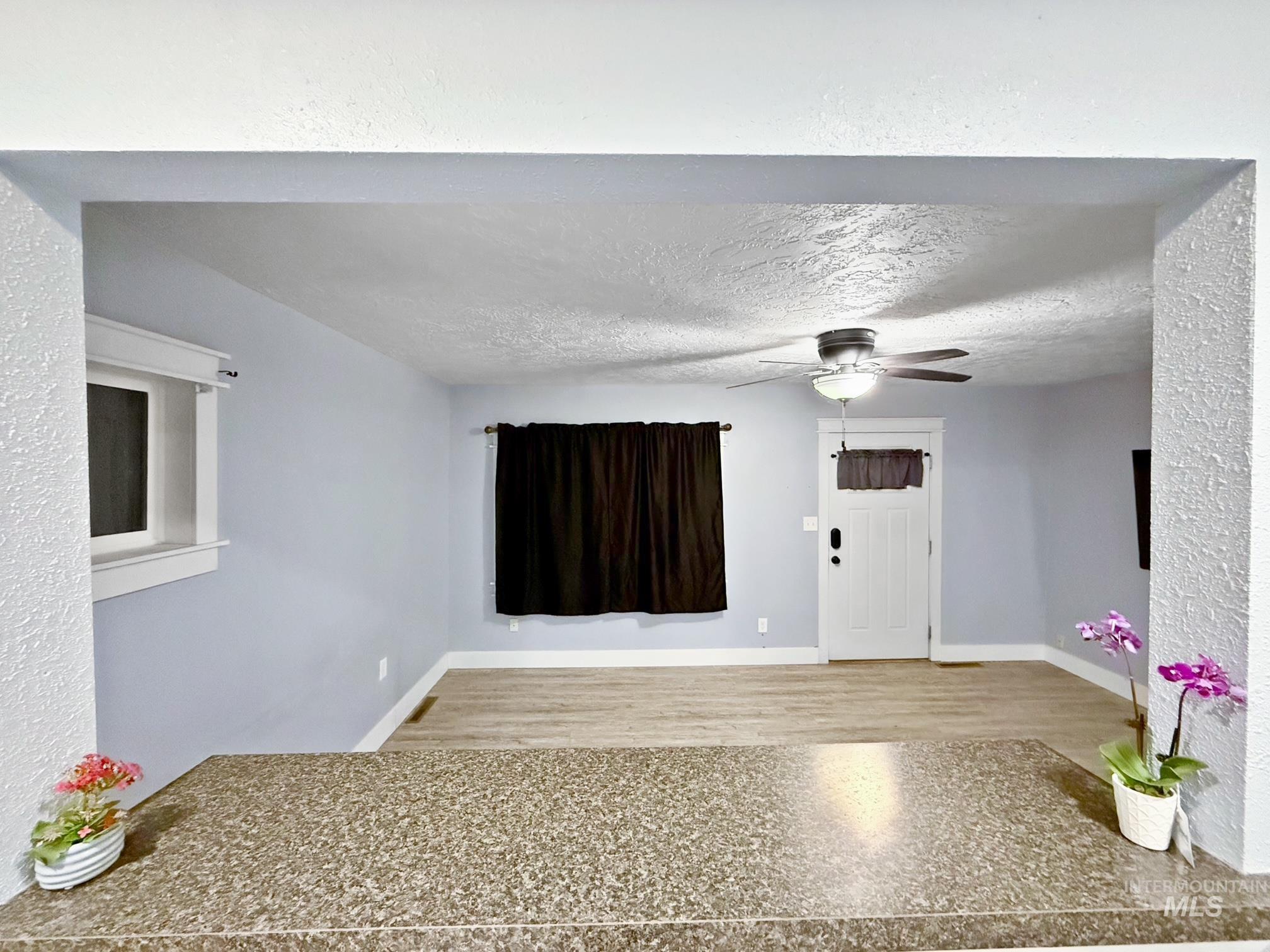 Entrance foyer with a textured ceiling, ceiling fan, and wood finished floors