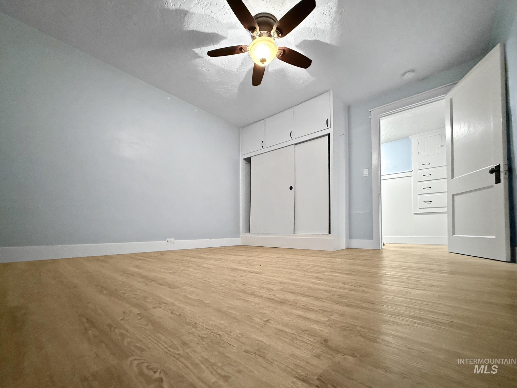 Unfurnished bedroom featuring light wood-type flooring, ceiling fan, and a textured ceiling