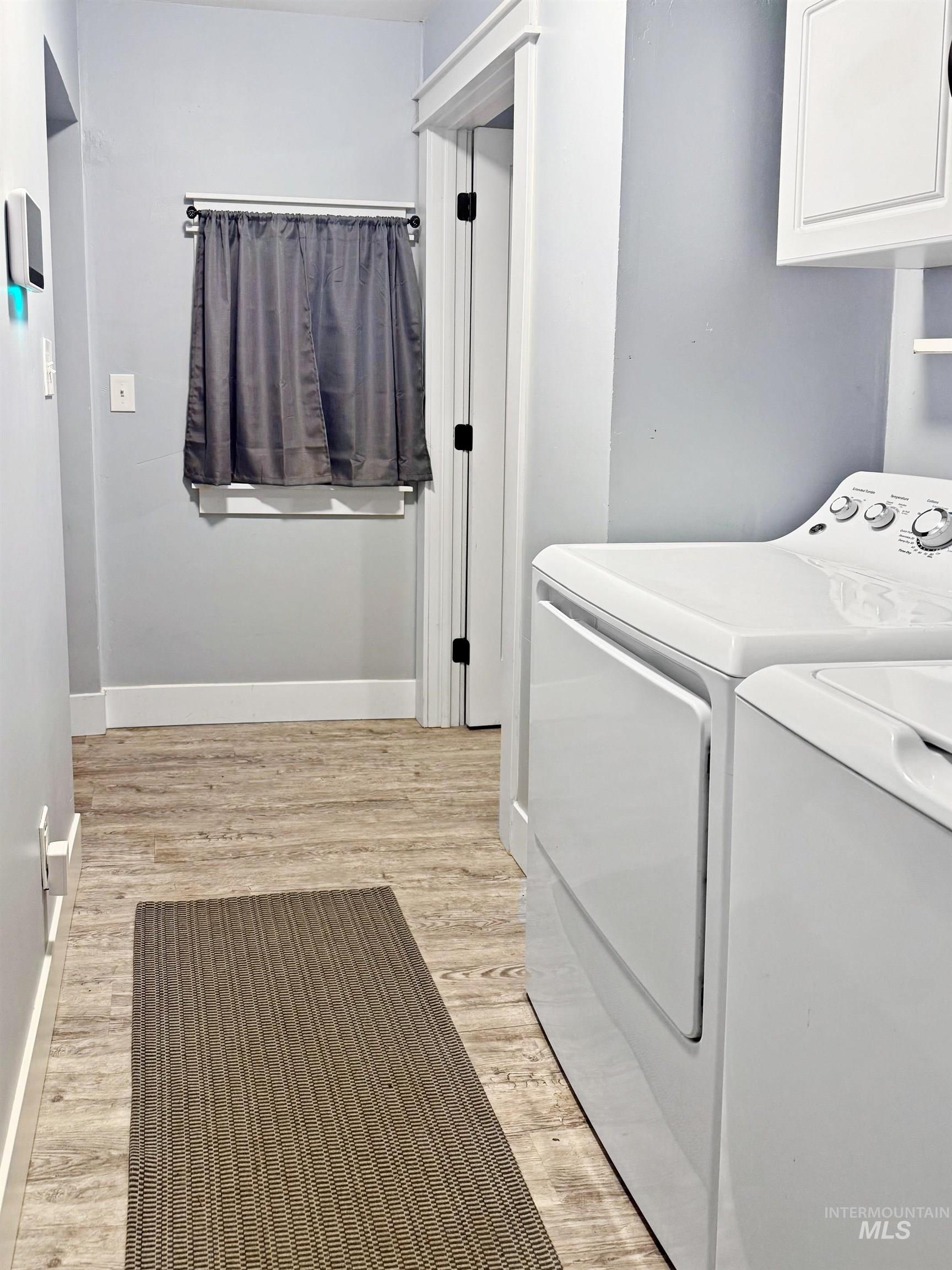 Washroom with light wood-style flooring and separate washer and dryer