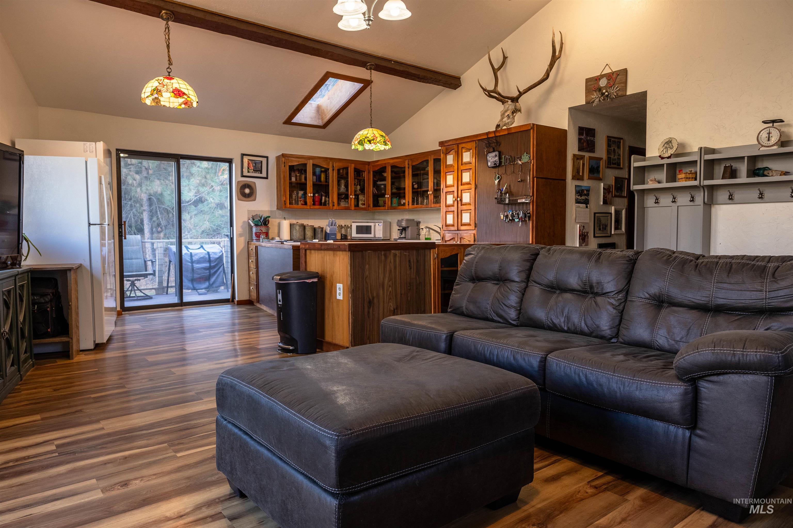 Living room with beam ceiling, dark wood-style flooring, a skylight, and high vaulted ceiling