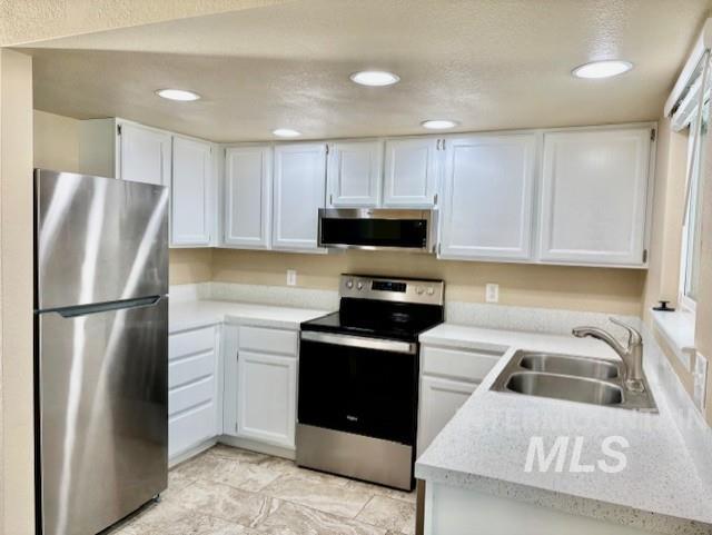 Kitchen with appliances with stainless steel finishes, light countertops, white cabinetry, and recessed lighting