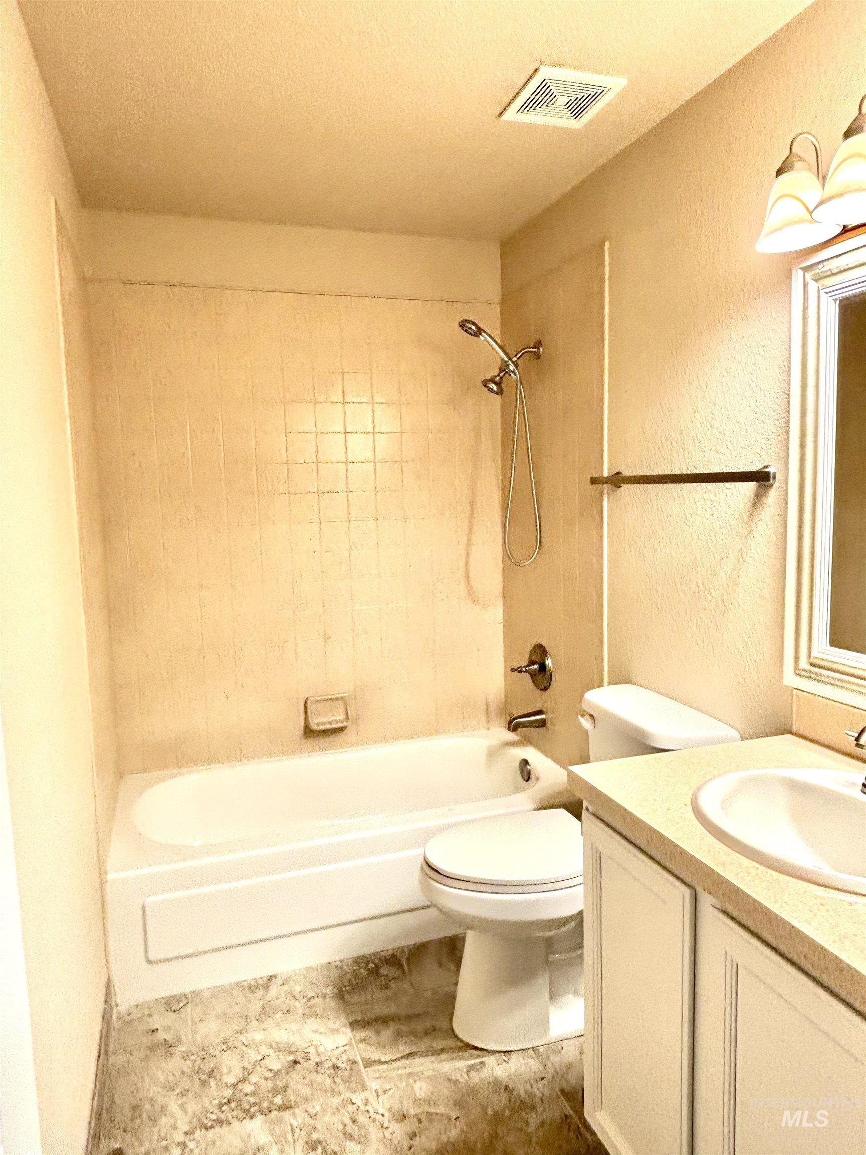 Bathroom with vanity, shower / bath combination, a textured ceiling, and a textured wall