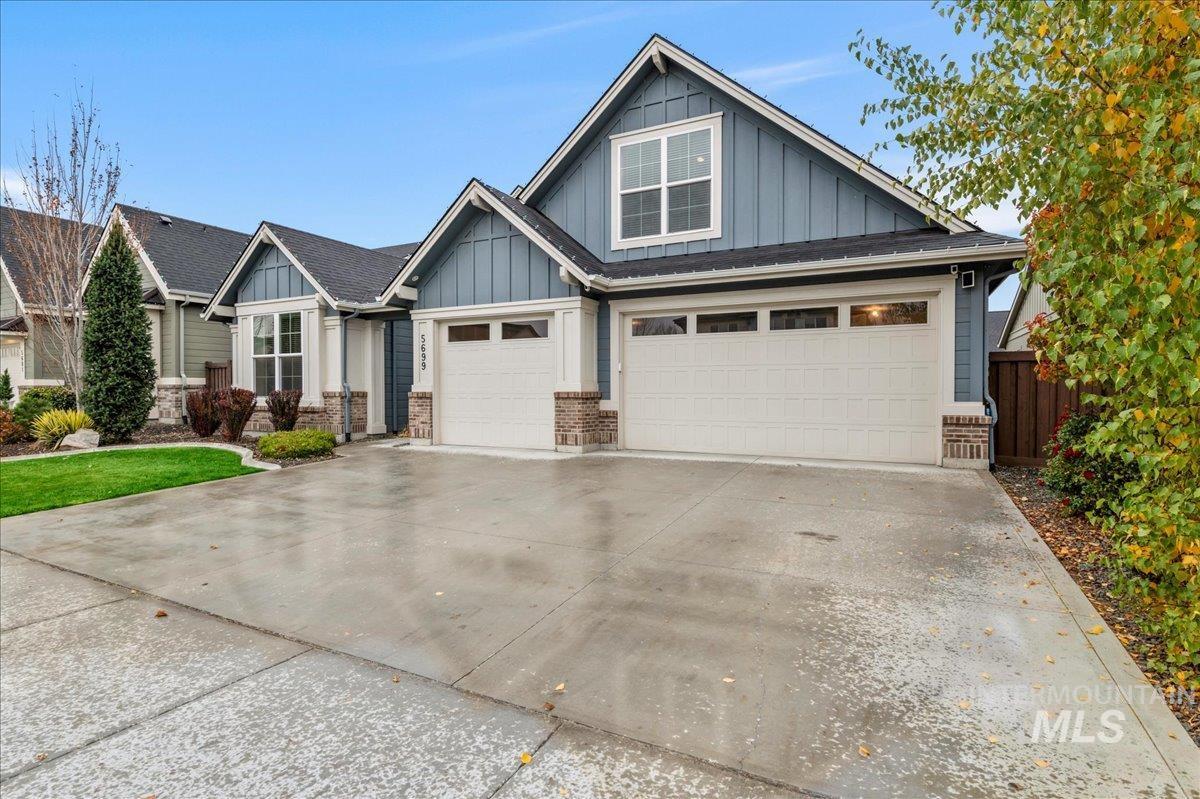 Craftsman house featuring board and batten siding, concrete driveway, and brick siding