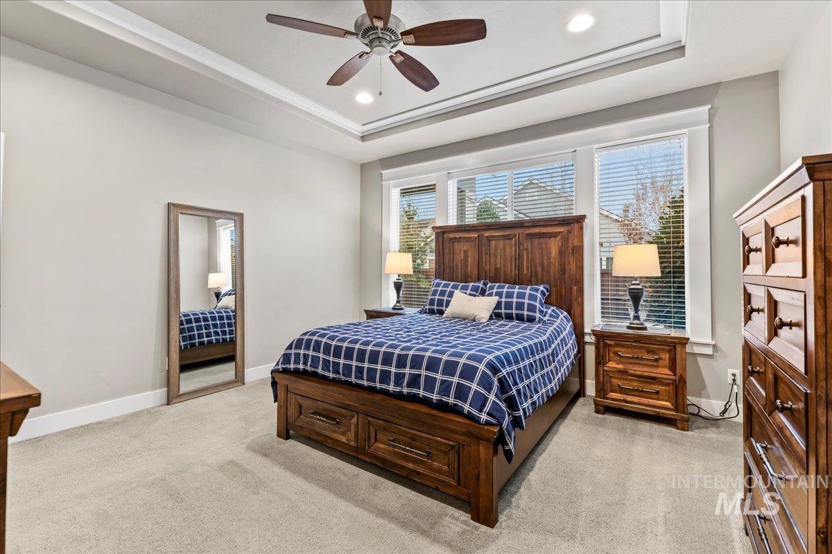 Bedroom featuring a raised ceiling, light colored carpet, a ceiling fan, and recessed lighting