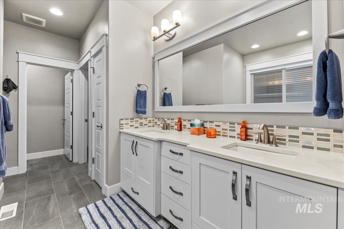 Full bath with decorative backsplash, double vanity, recessed lighting, a closet, and dark tile patterned floors