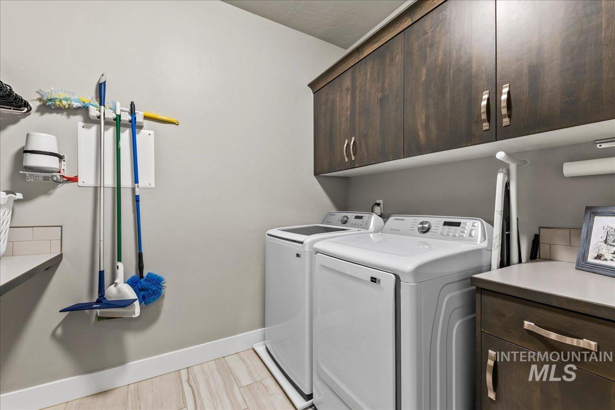 Laundry room featuring cabinet space, separate washer and dryer, and light wood-style flooring