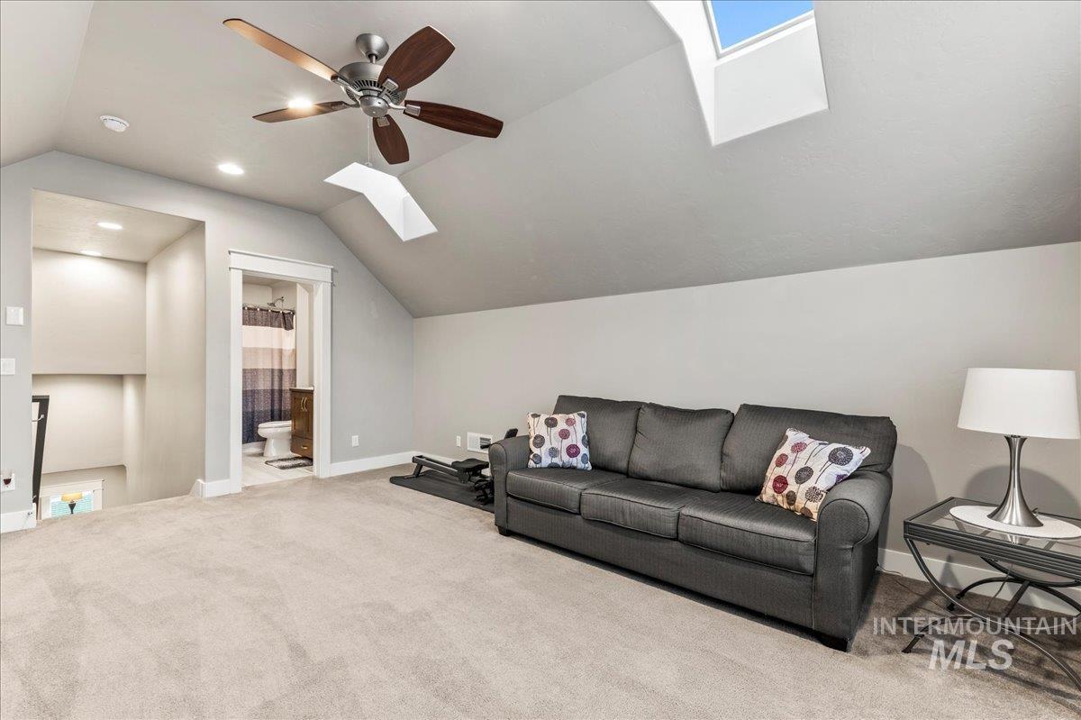 Carpeted living area with a skylight, lofted ceiling, recessed lighting, and ceiling fan