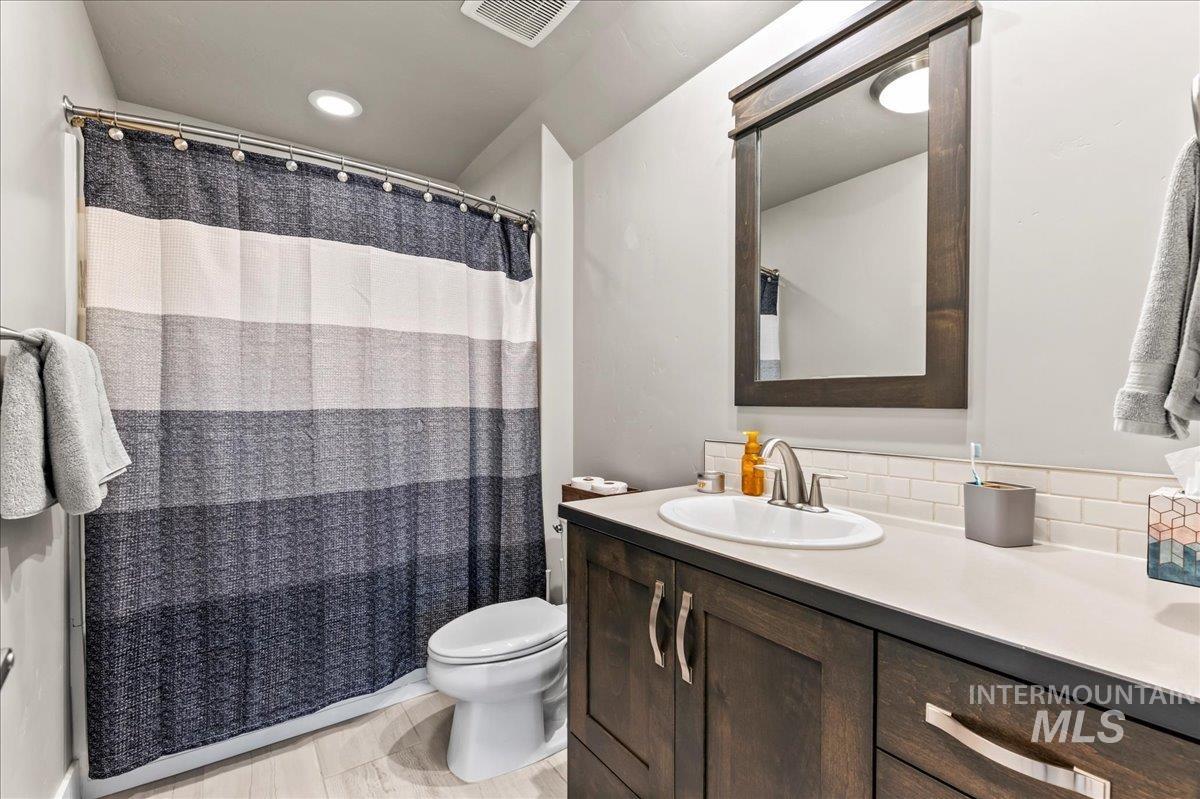 Bathroom featuring double vanity, a shower with curtain, and backsplash