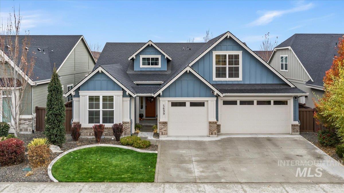 Craftsman-style home with board and batten siding, driveway, roof with shingles, brick siding, and an attached garage
