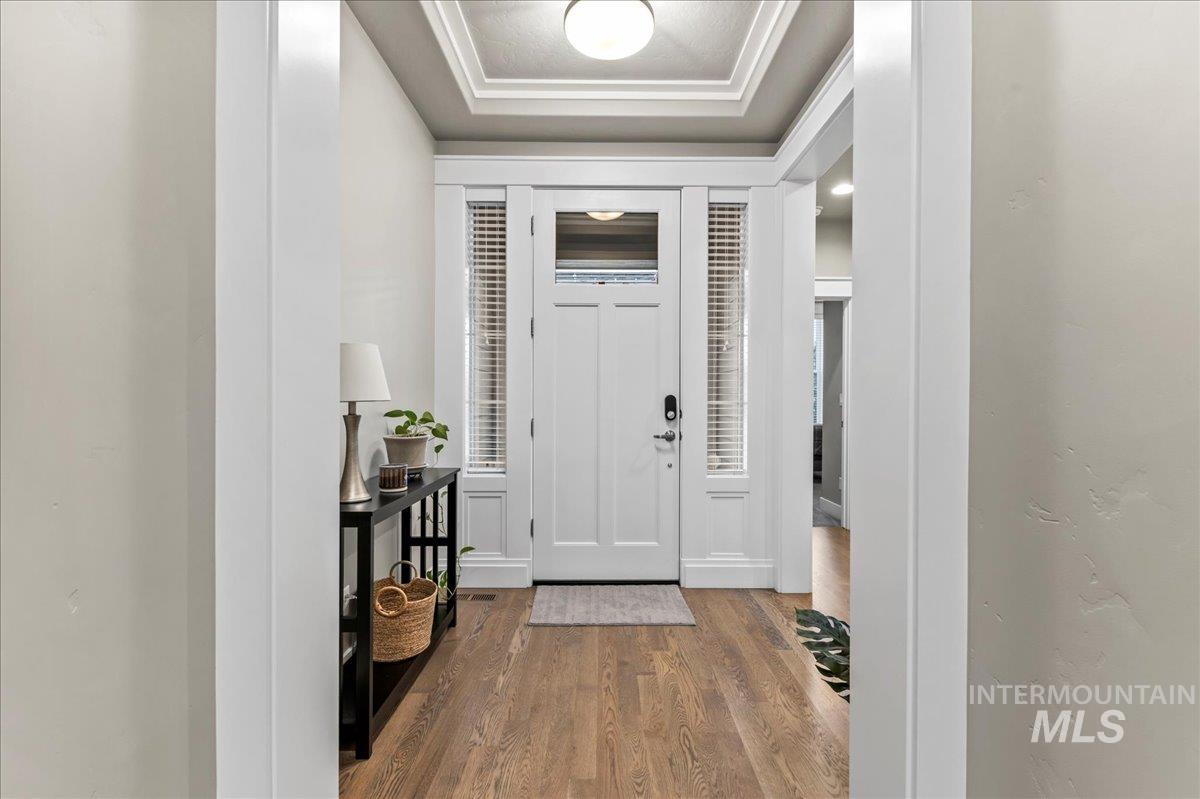 Entryway with dark wood-style flooring and a tray ceiling
