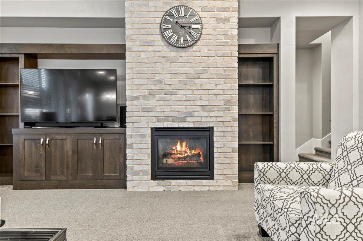 Carpeted living room with a fireplace and built in features