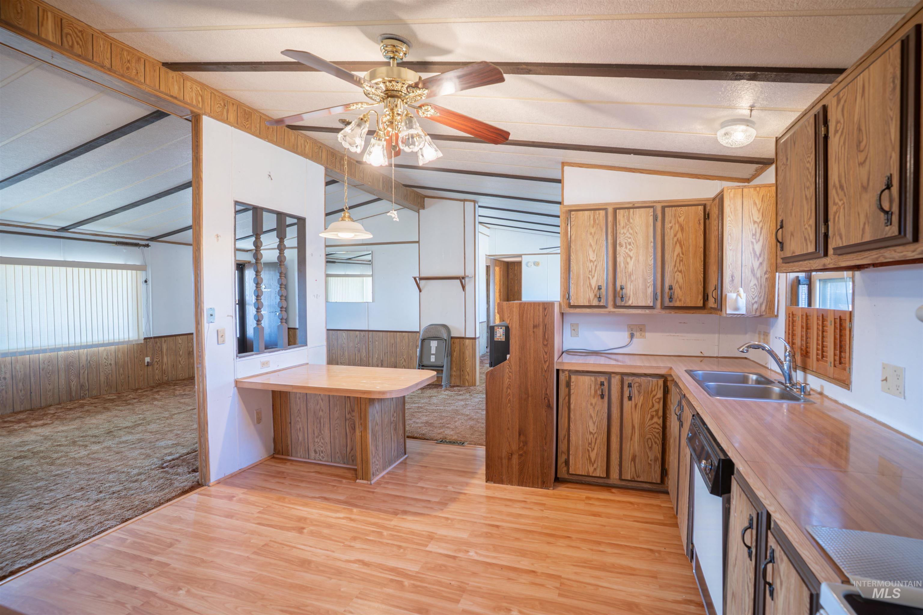 Kitchen featuring brown cabinetry, wainscoting, wooden walls, a peninsula, and light wood-style floors