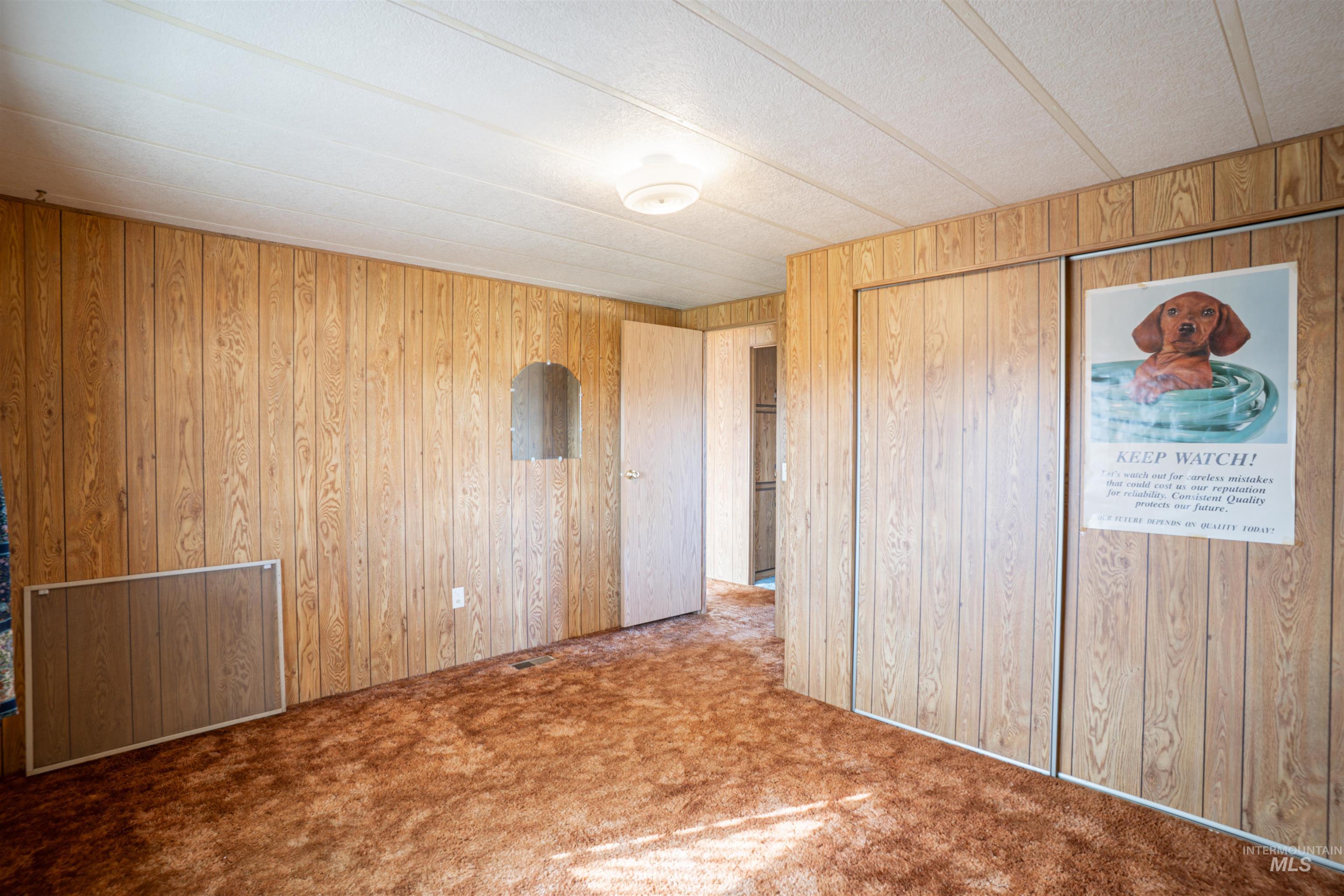 Unfurnished bedroom with carpet floors and wood walls
