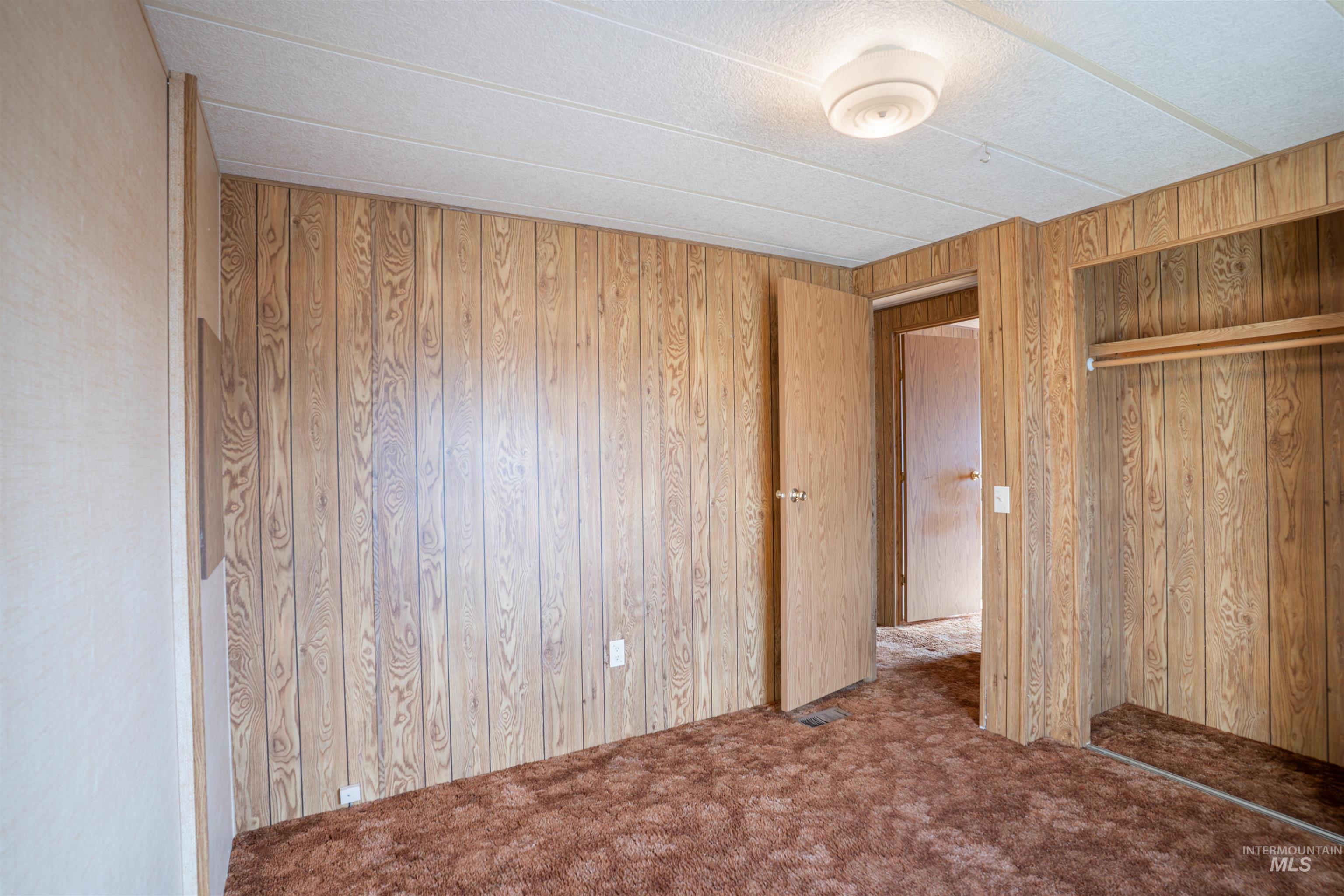 Unfurnished bedroom featuring carpet, a closet, and wooden walls